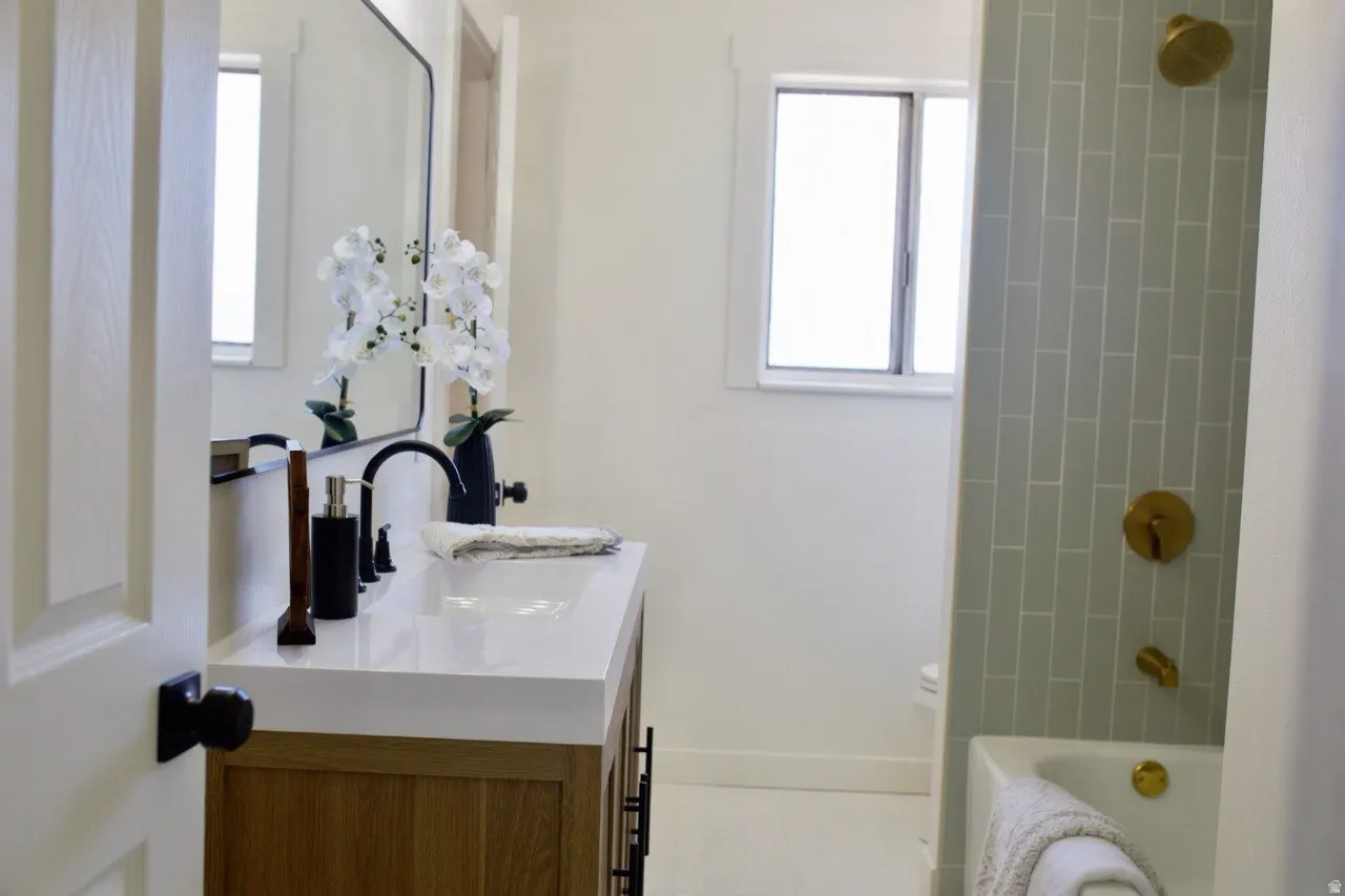 Bathroom featuring a wood-finish vanity with a white countertop, a black framed mirror, and a black faucet