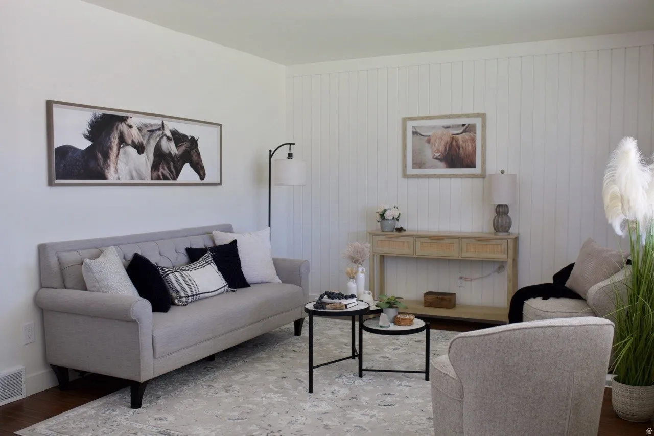 Bright living area featuring wood-finish flooring and a light-toned area rug