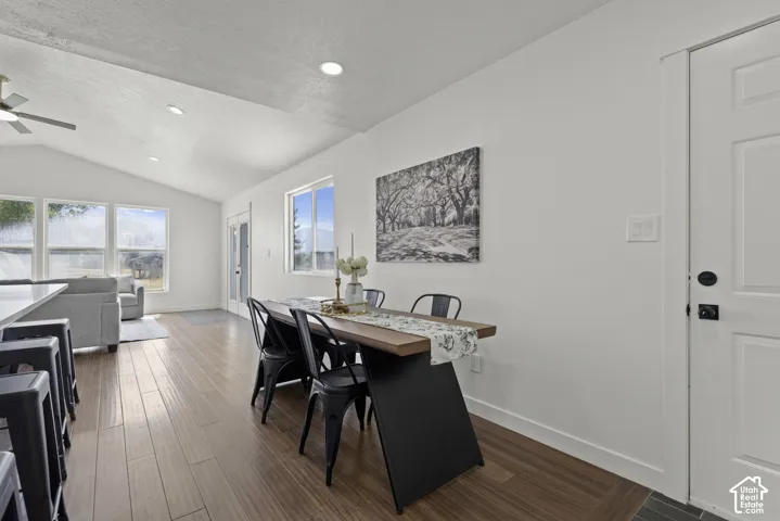 Vaulted ceiling, wood-finish flooring, white walls, multiple windows, and recessed lighting