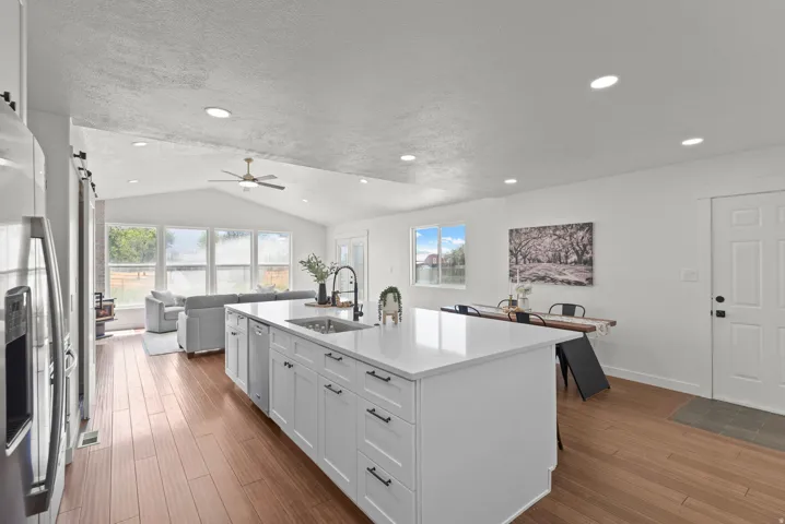 Open-concept living area featuring wood-finish flooring, a vaulted ceiling, and recessed lighting