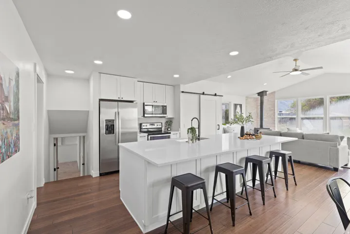 Kitchen featuring white cabinetry, stainless steel appliances, a large island with seating, and wood-finish flooring