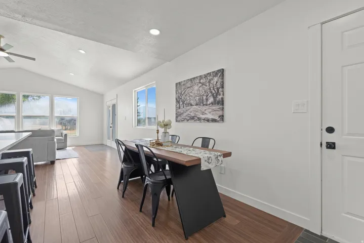Vaulted ceiling, wood-finish flooring, white walls, multiple windows, and recessed lighting
