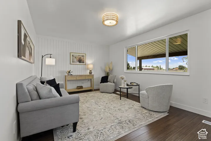 Rich wood-finish flooring, white shiplap accent wall, and a large multi-pane window