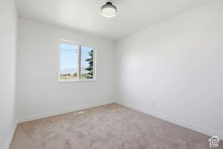 Carpeted room featuring a single window, white walls, and a ceiling-mounted light fixture