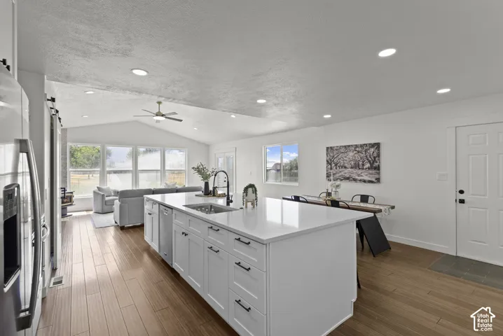 Open-concept living area featuring wood-finish flooring, a vaulted ceiling, and recessed lighting