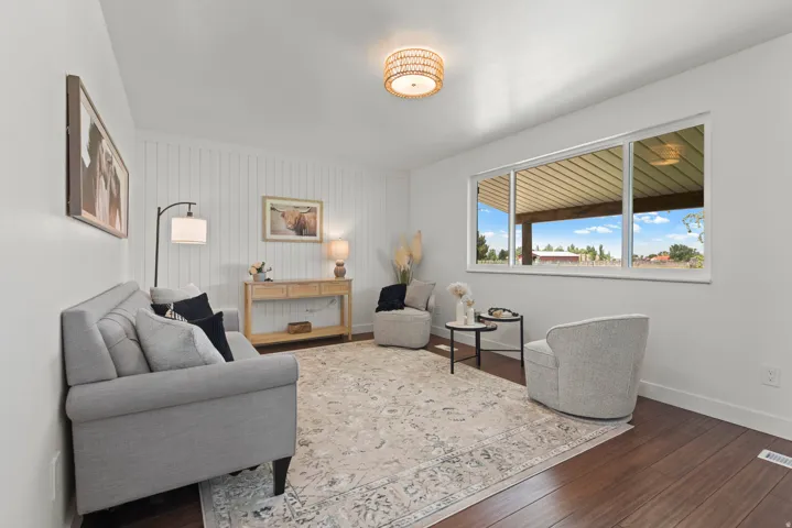 Rich wood-finish flooring, white shiplap accent wall, and a large multi-pane window