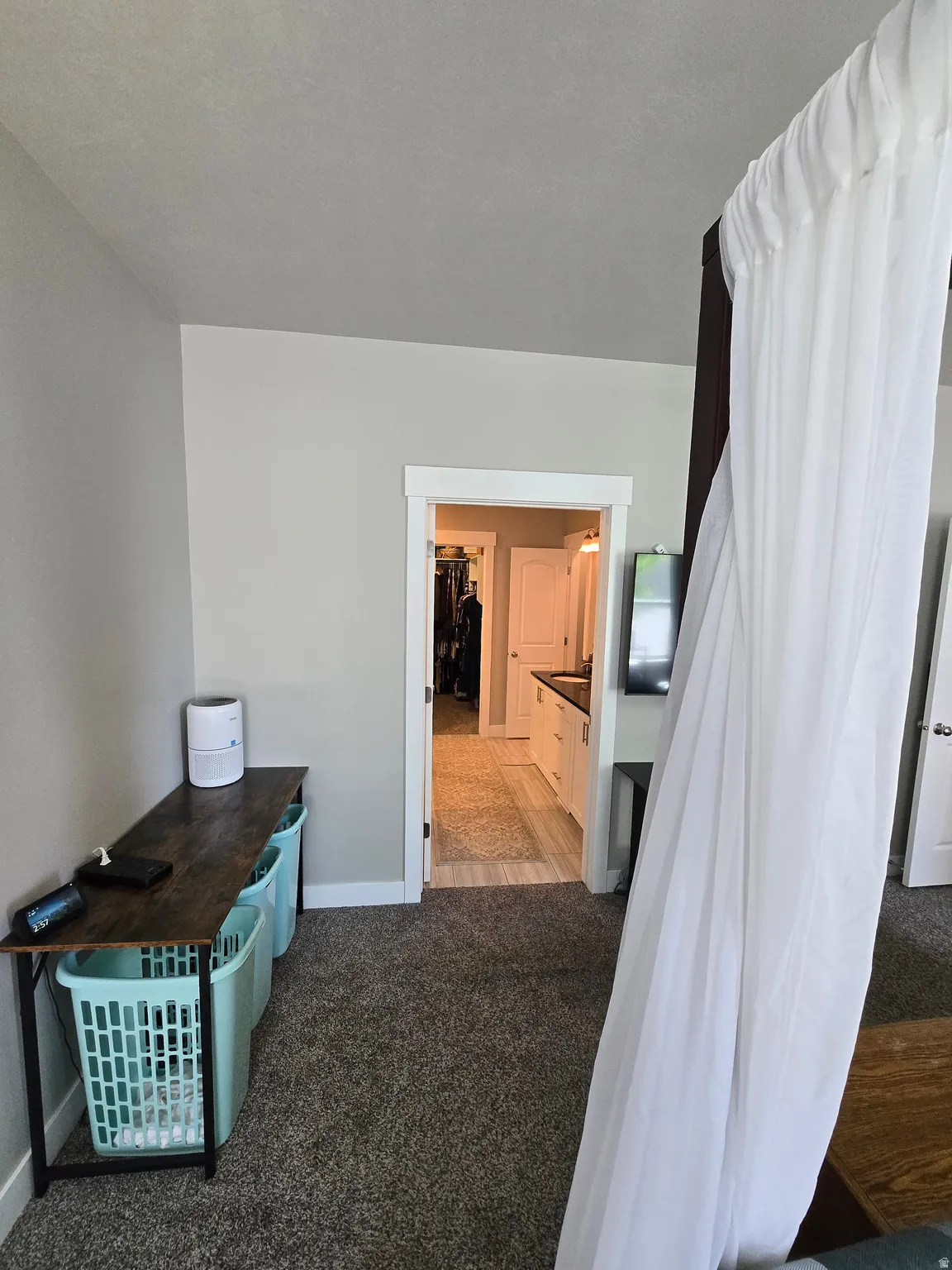 Carpeted room with a doorway leading to a tiled area, offering a glimpse of built-in cabinetry and a second doorway