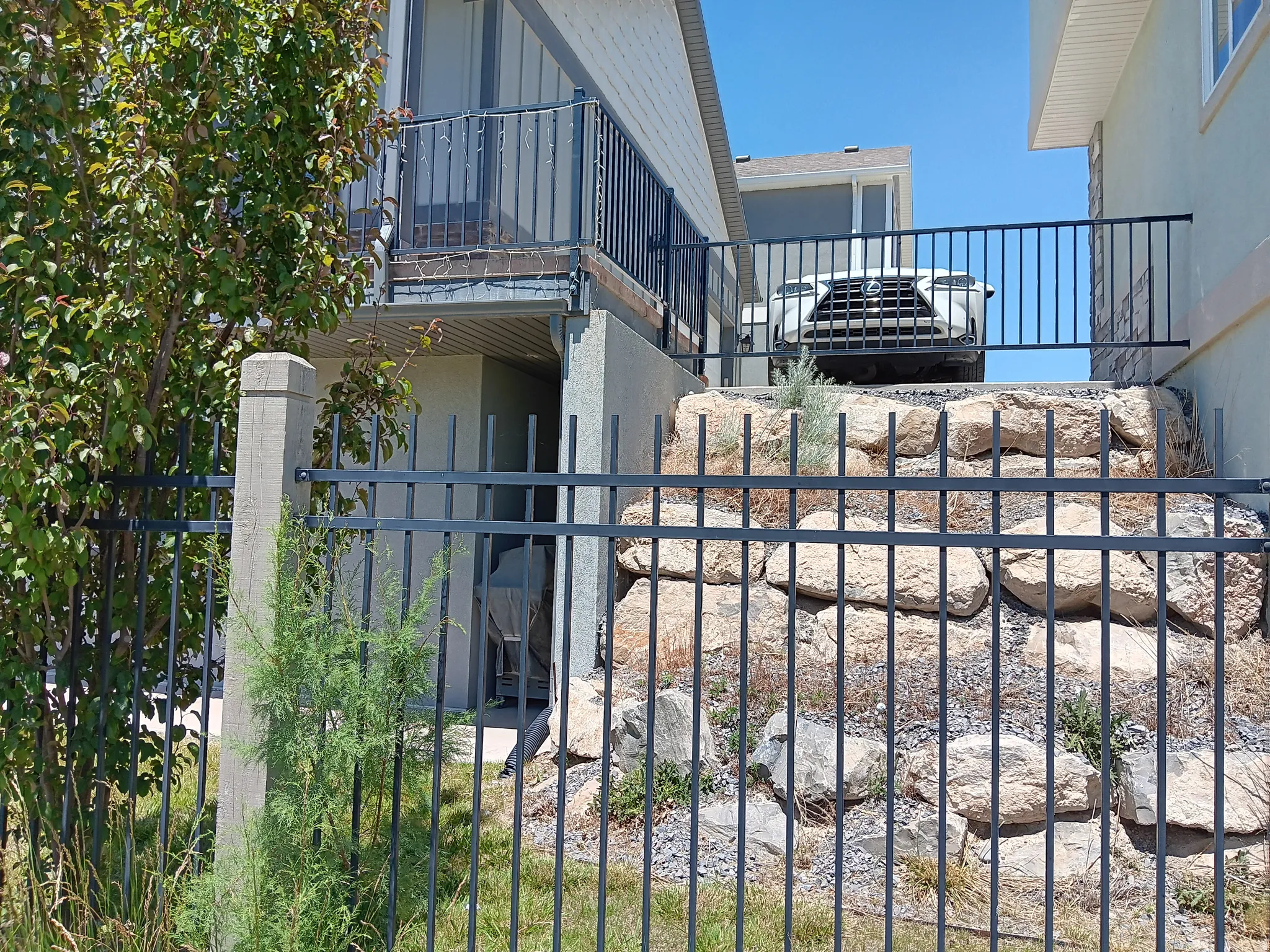 Black wrought iron fencing enclosing a stone retaining wall and a concrete pillar
