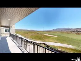 Covered patio featuring an expansive golf course and mountain backdrop