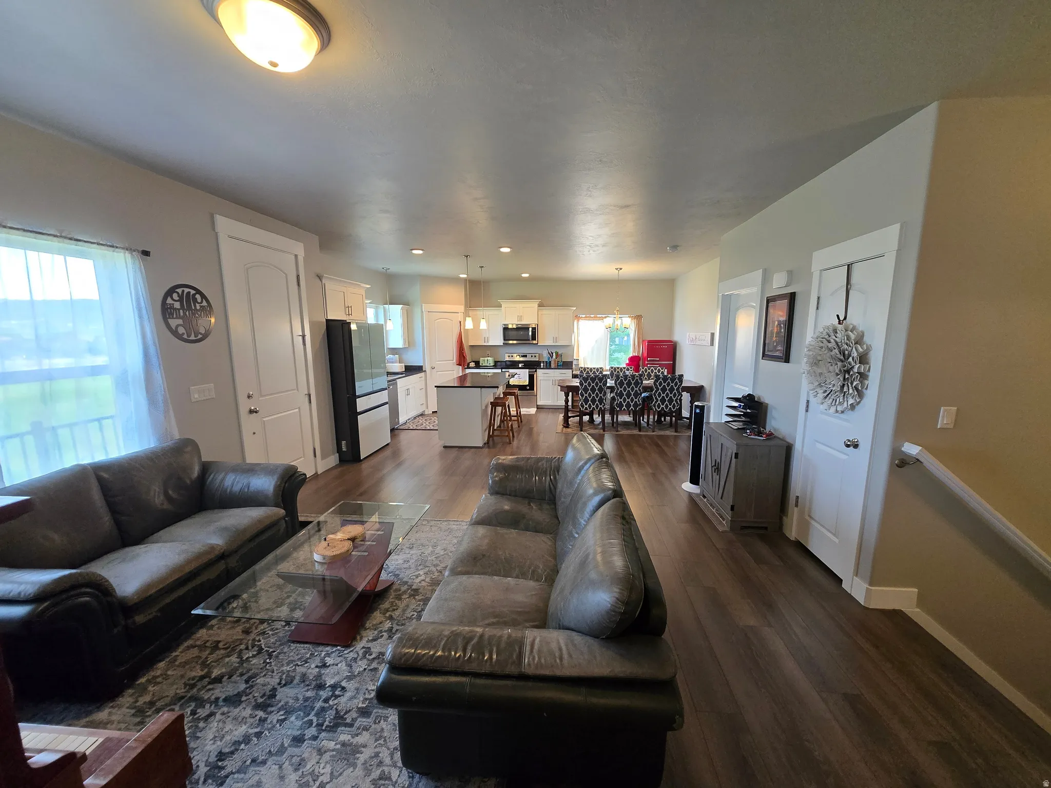 Open-concept living area featuring wood-finish flooring, recessed lighting, and a bright window