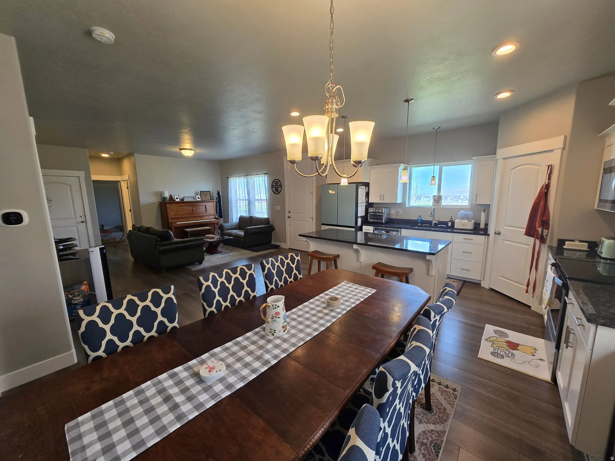 Open-concept living space featuring wood-finish flooring, a dining area, and a kitchen with white cabinetry and dark countertops