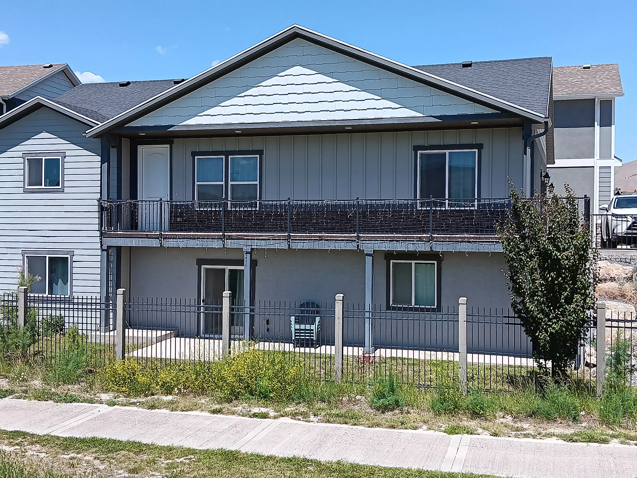 Multi-level residence featuring a gray vertical siding facade and a light blue shingle-style gable accent