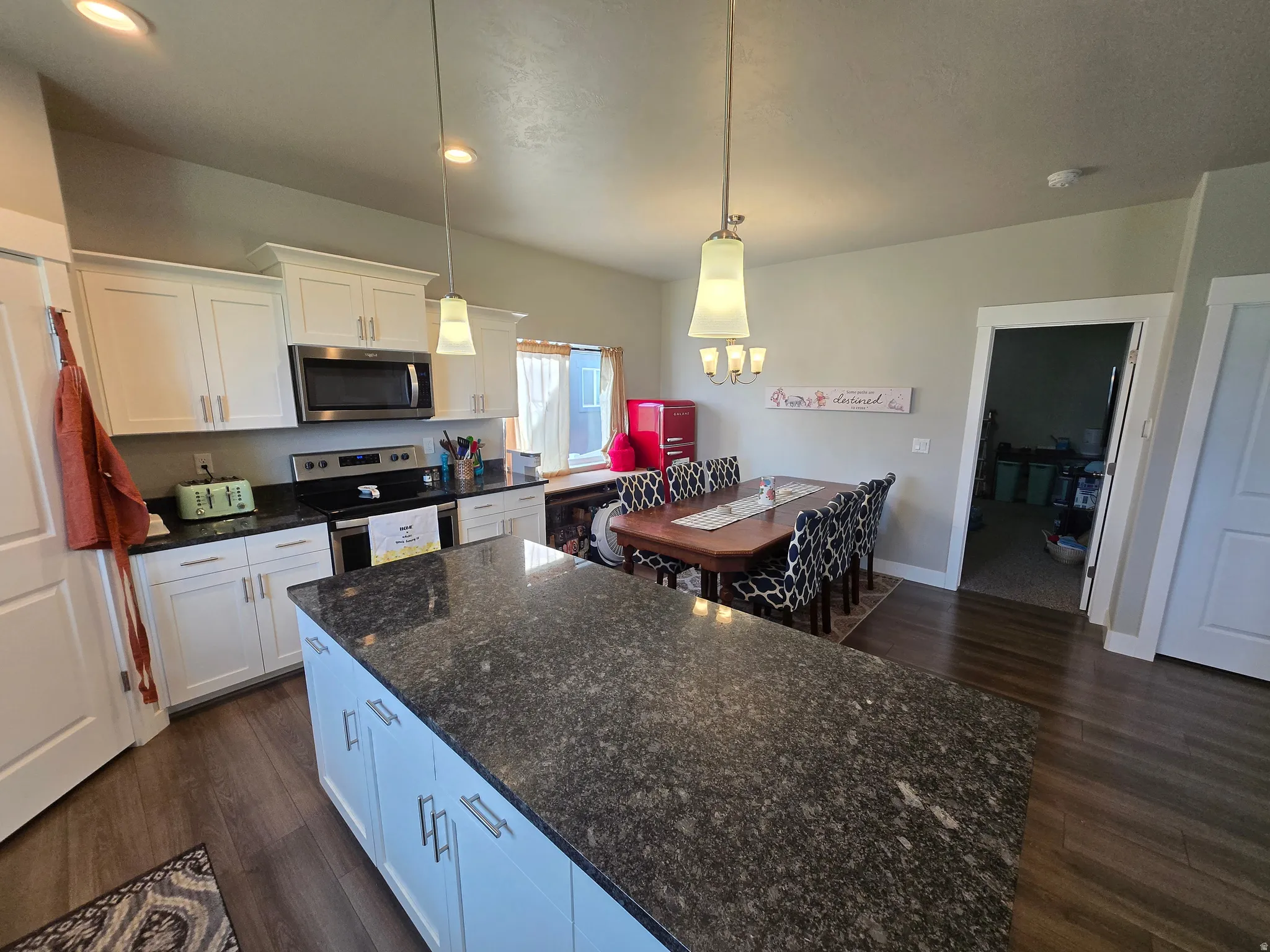 Kitchen featuring a large island with a dark speckled countertop, white cabinetry with silver hardware, wood-finish flooring, and recessed lighting