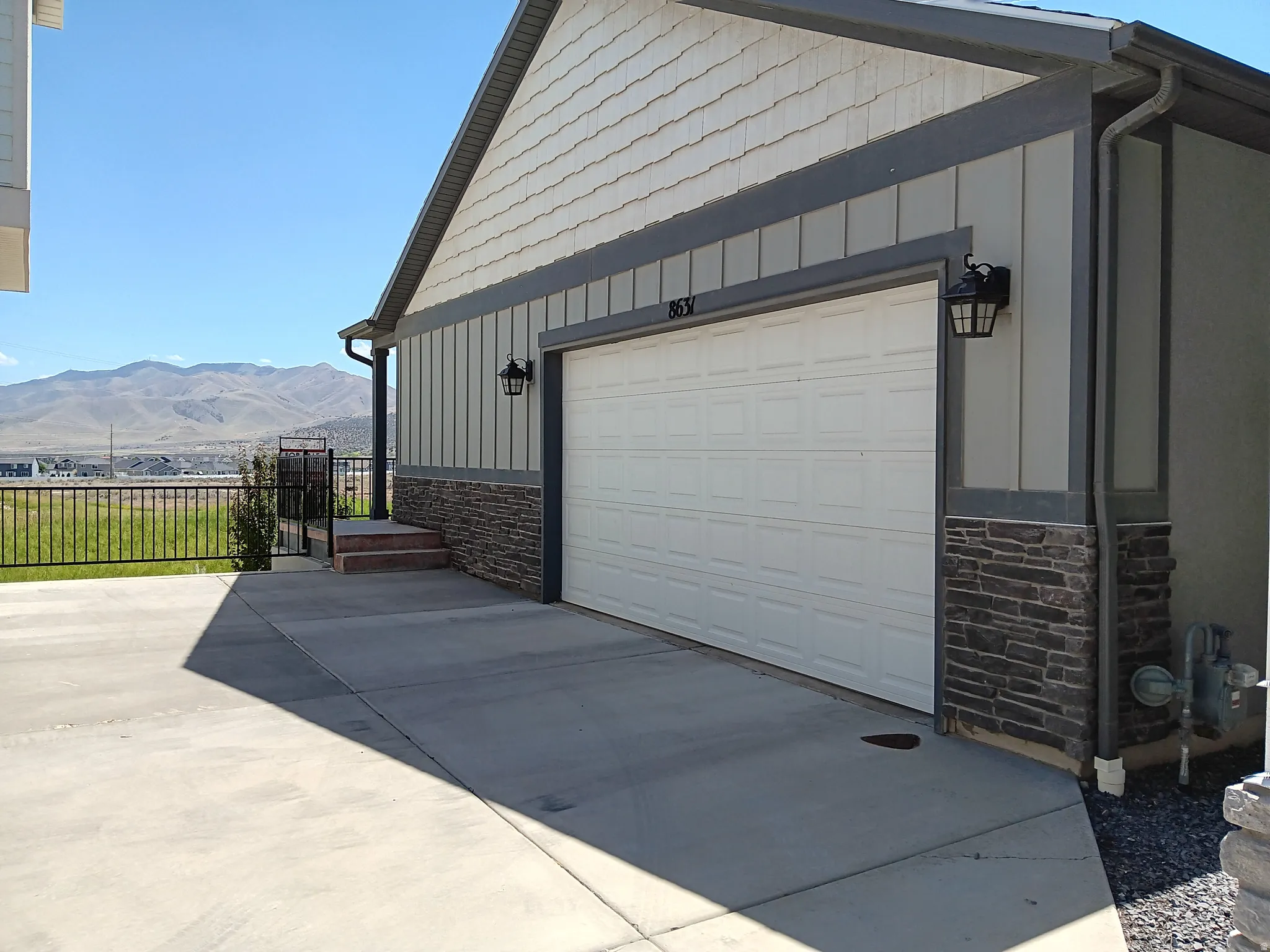 Exterior featuring a white garage door, stacked stone accents, and vertical siding