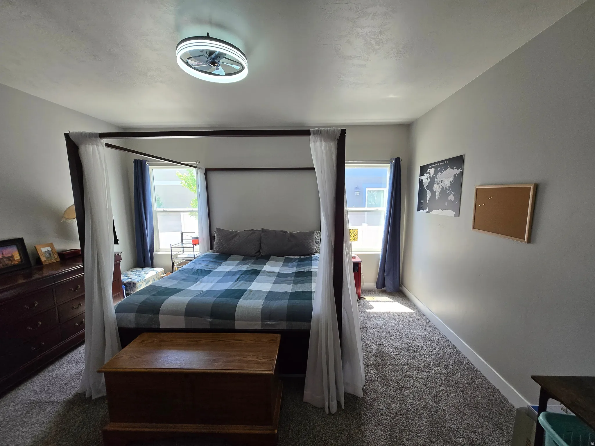 Carpeted bedroom featuring a ceiling-mounted light fixture with integrated fan, light gray wall paint, and white baseboards
