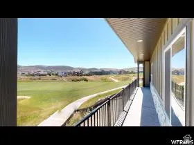 Covered balcony with black metal railings overlooking a golf course