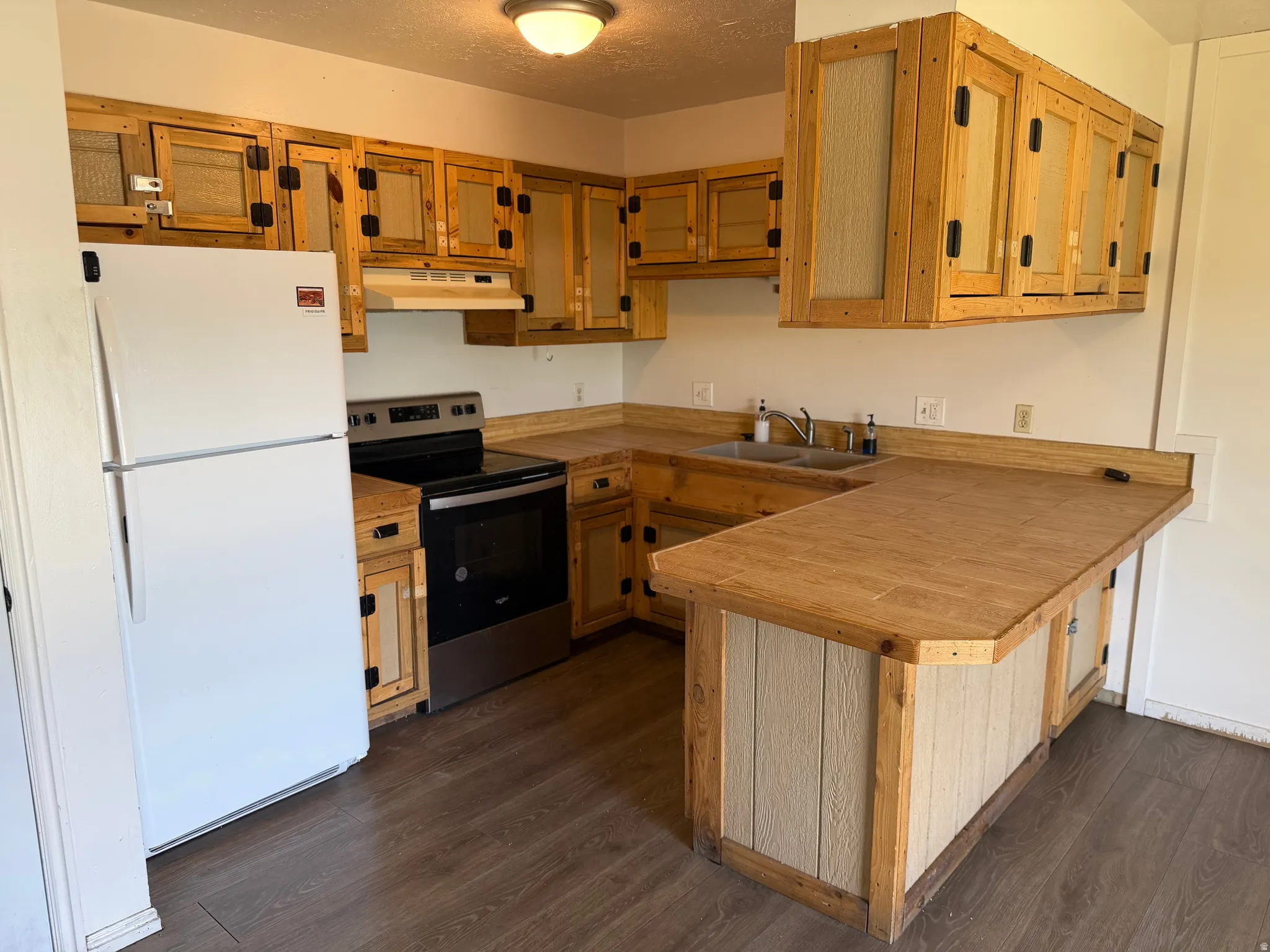 Kitchen featuring wood-finish cabinetry, wood-finish countertops, and wood-finish flooring