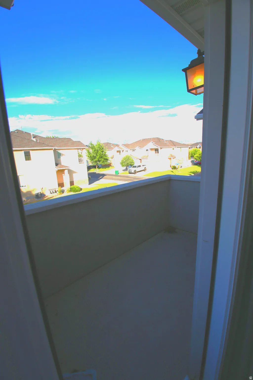 Outdoor balcony featuring a painted concrete surface, a solid privacy wall, and an attached exterior light fixture