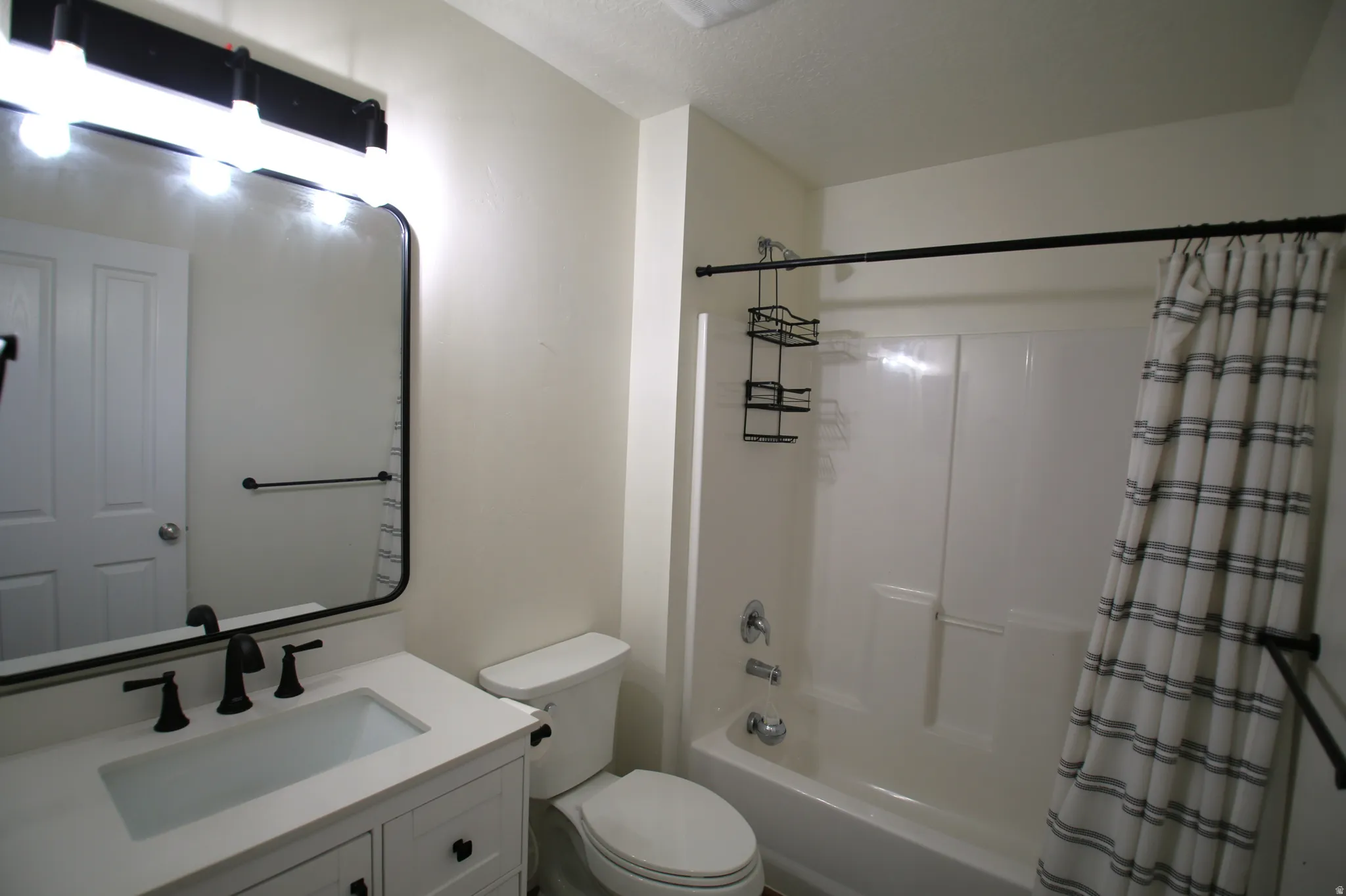 Bathroom featuring a white vanity with integrated sink, matte black faucet, and coordinating black-framed mirror