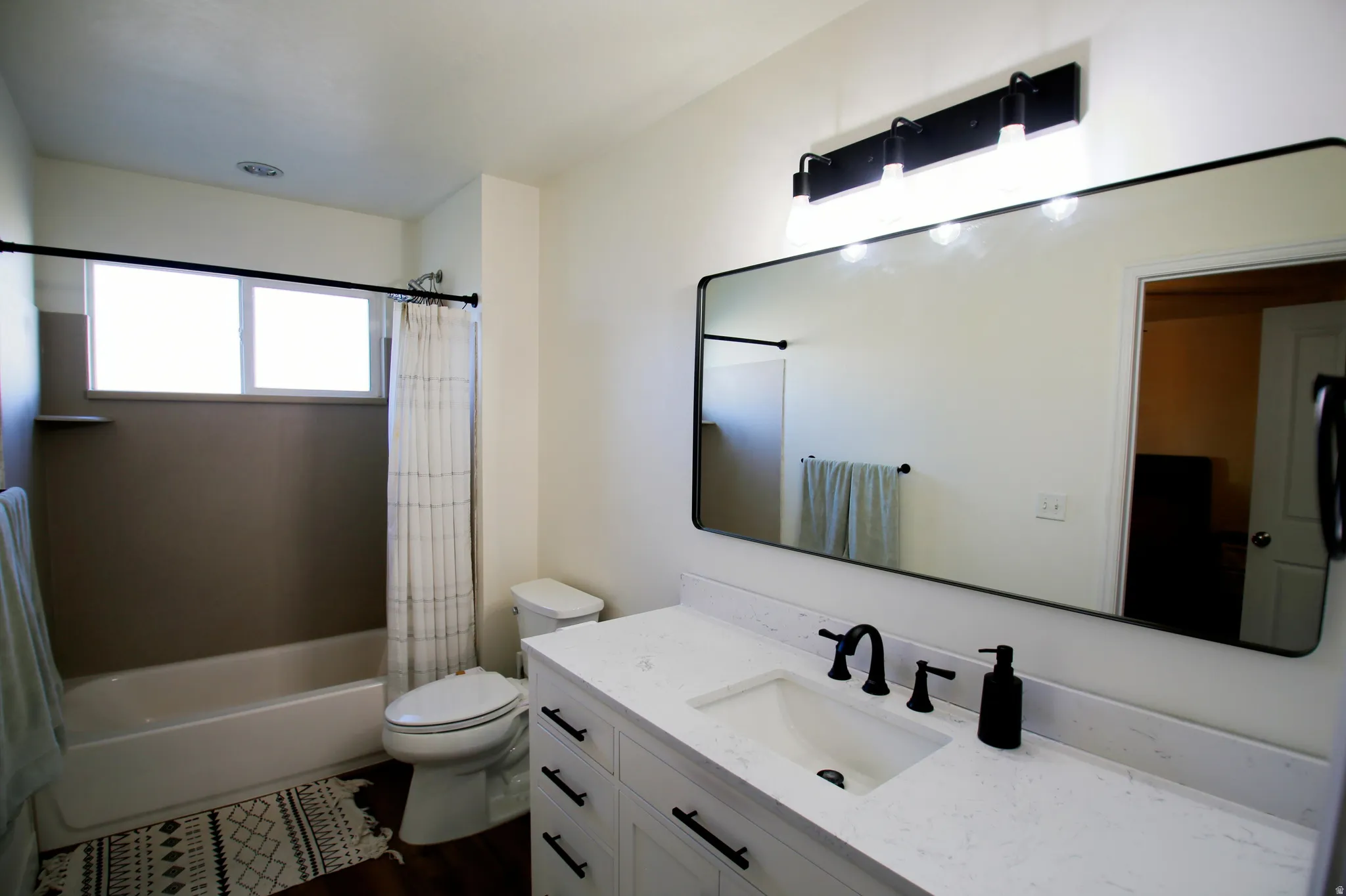 Bathroom featuring a white vanity with black hardware, white countertop, and integrated sink