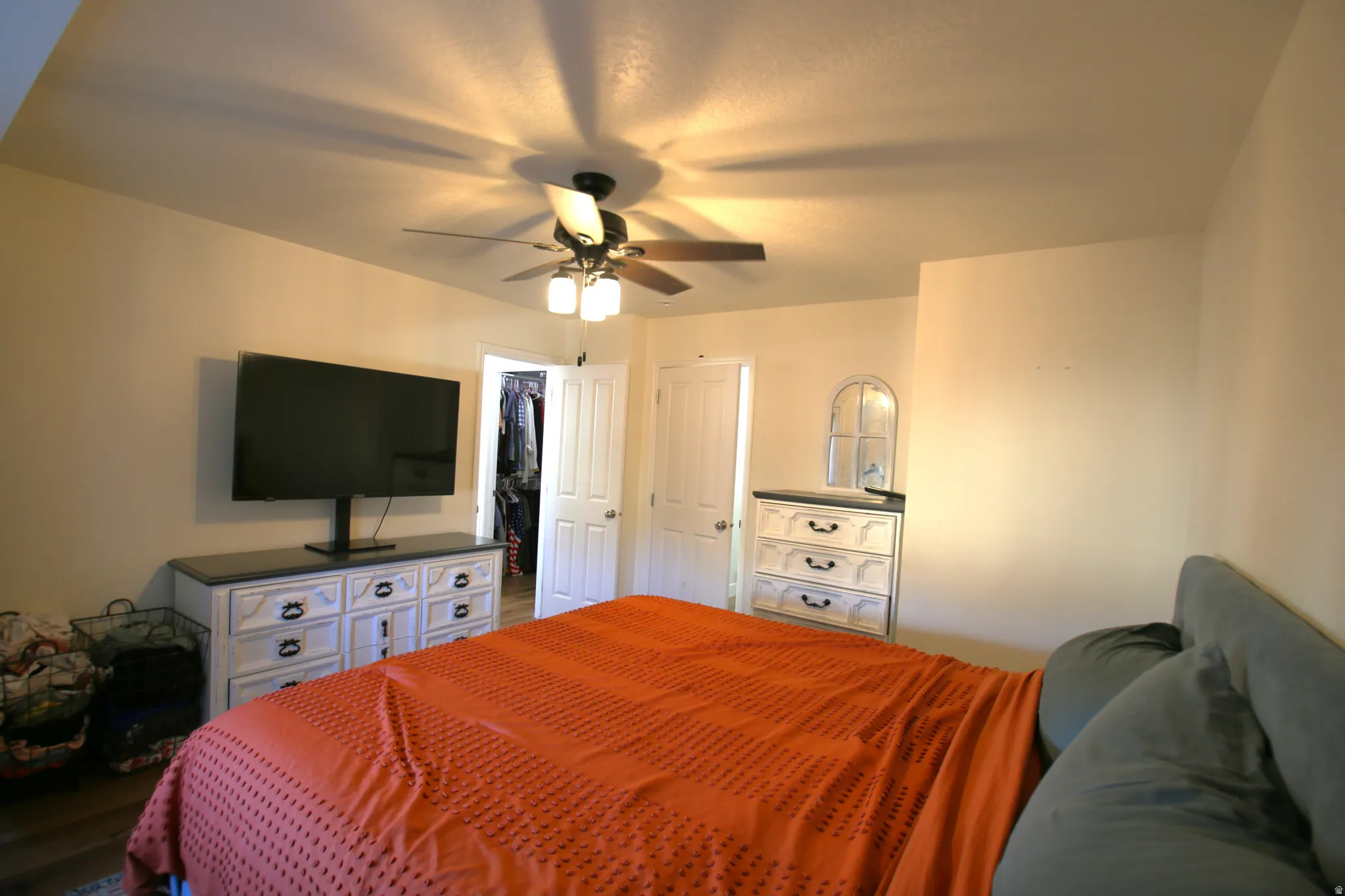Bedroom with wood-finish flooring, a ceiling fan with integrated lighting, and a closet with bifold doors