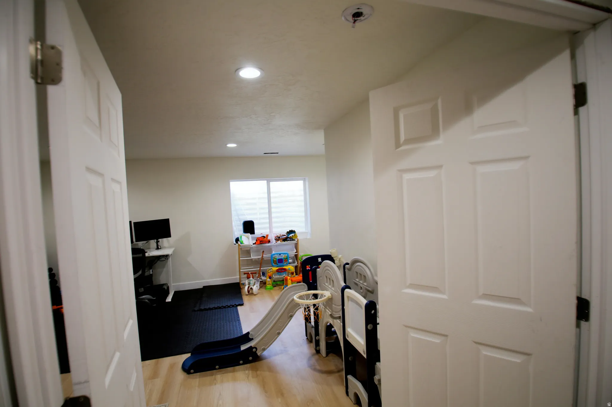 Interior space featuring light wood-finish flooring, recessed lighting, and a white paneled door