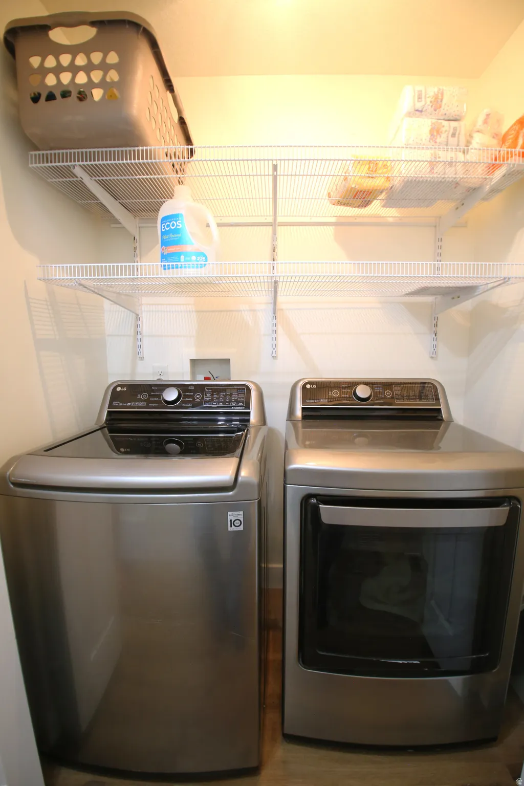 Dedicated laundry area featuring wire shelving, wood-finish flooring, and light-toned walls