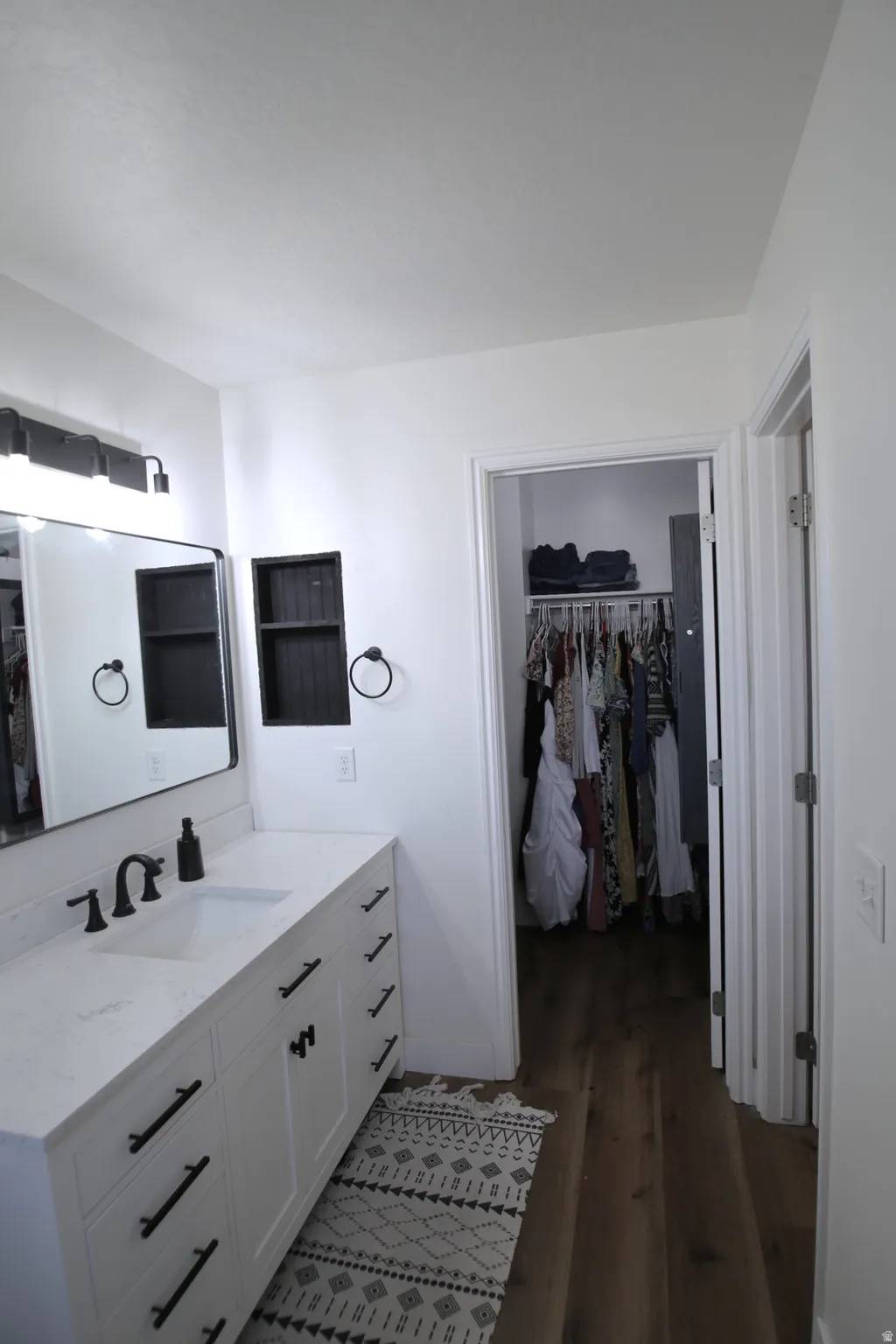 White vanity with black hardware, integrated rectangular sink, and quartz countertop