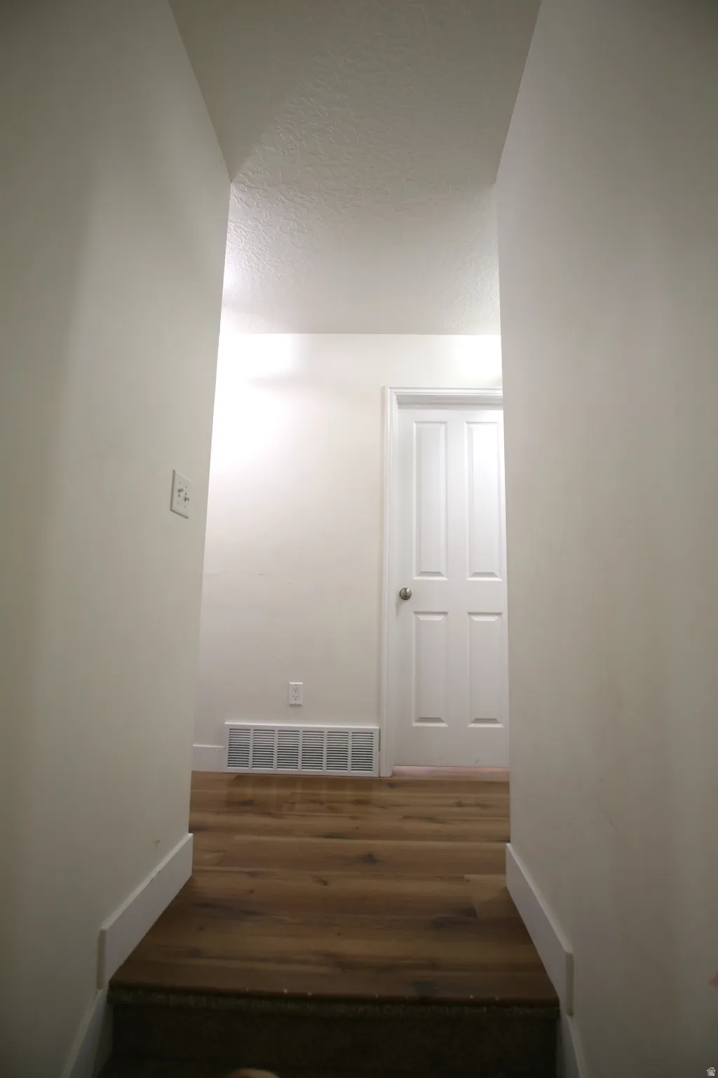Hallway featuring wood-finish flooring, white baseboards, and light-toned walls