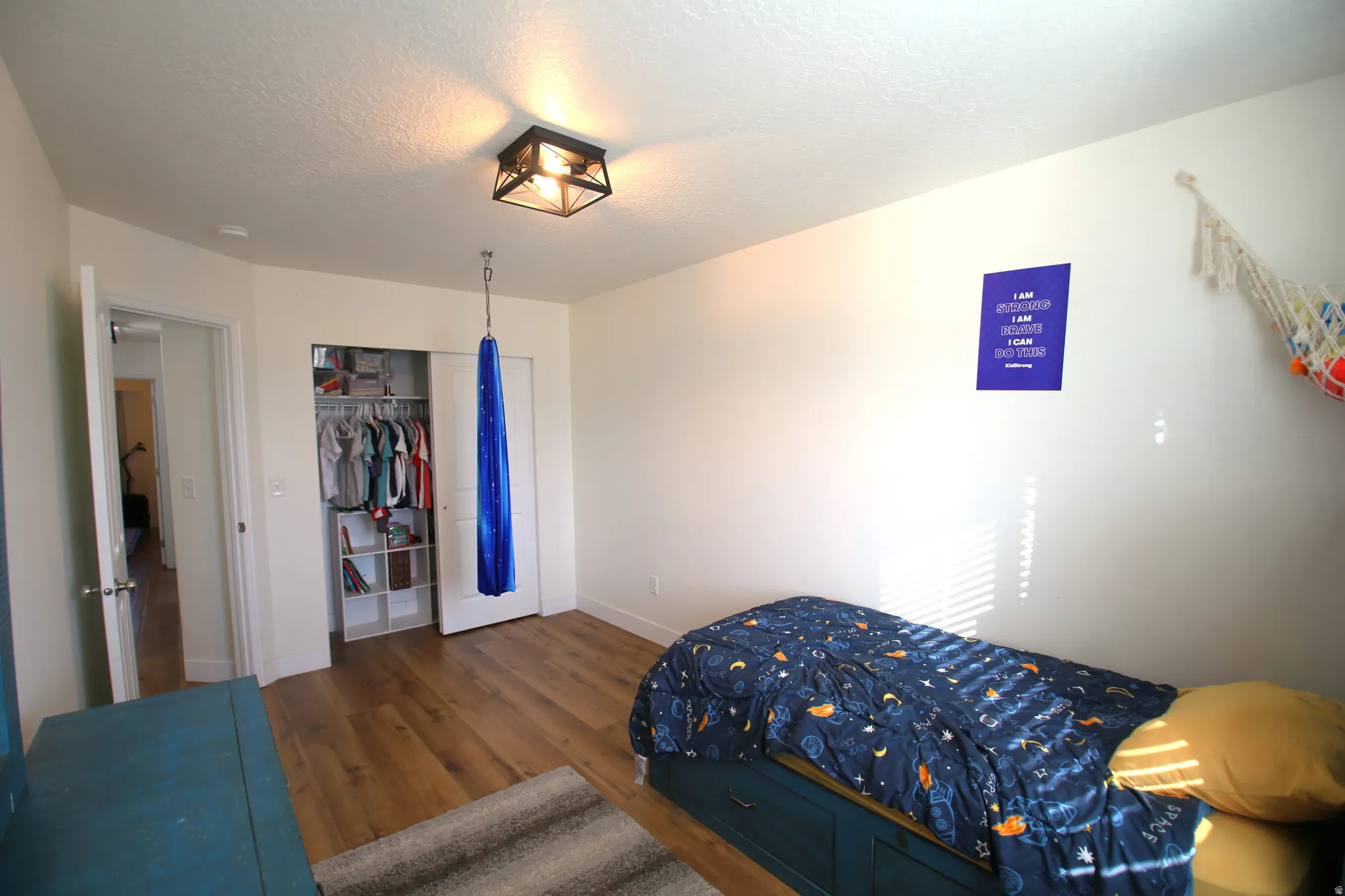 Hardwood-style flooring and neutral wall tones define this room, featuring a built-in closet with bifold doors and an overhead light fixture