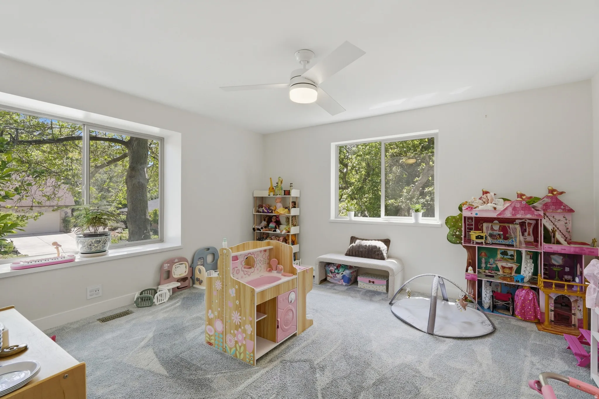Spacious room featuring multiple large windows, recessed lighting, a ceiling fan, light-toned walls, and patterned carpeting