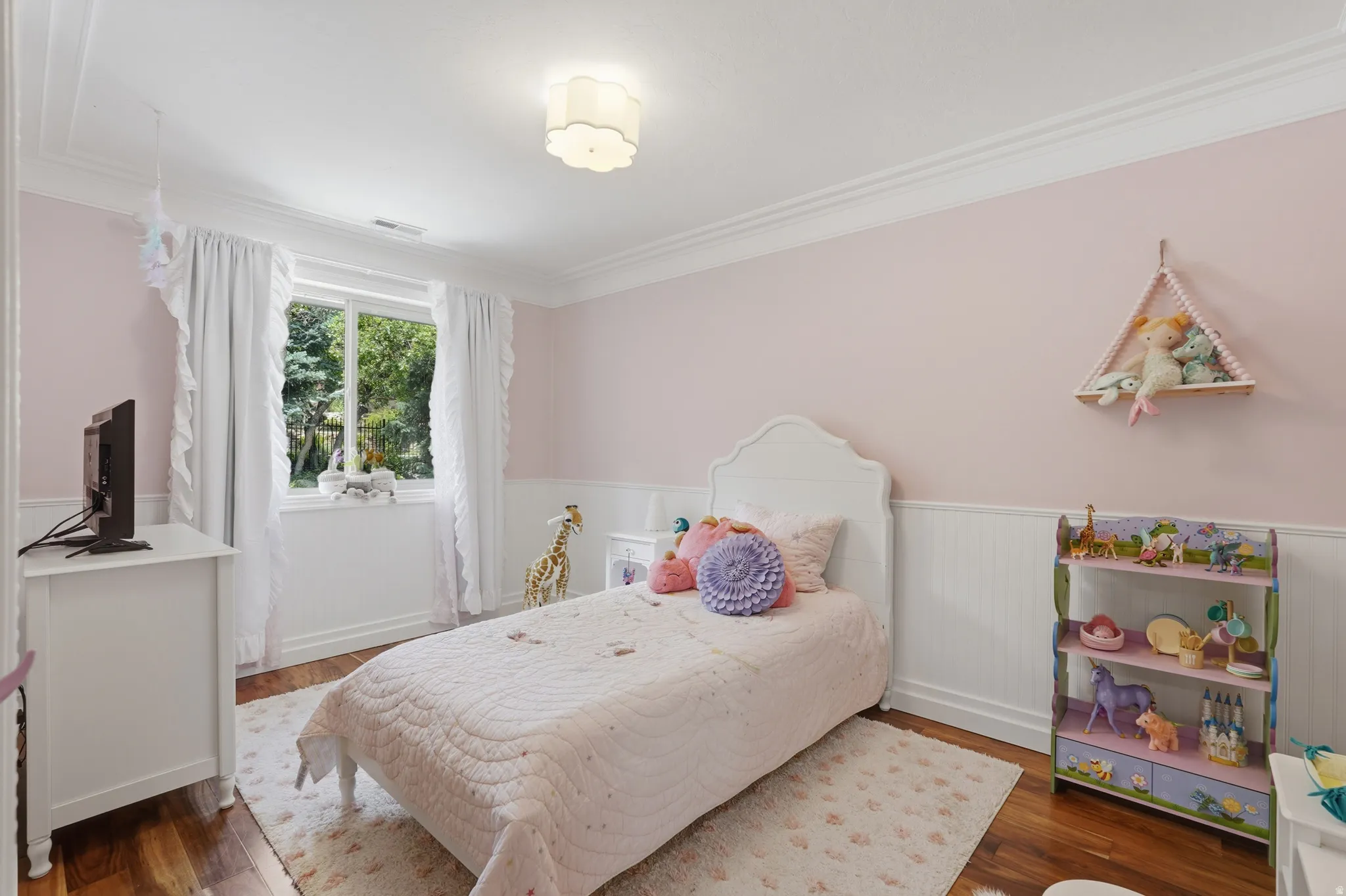 Interior room with hardwood-finish flooring, white crown molding, and white wainscoting