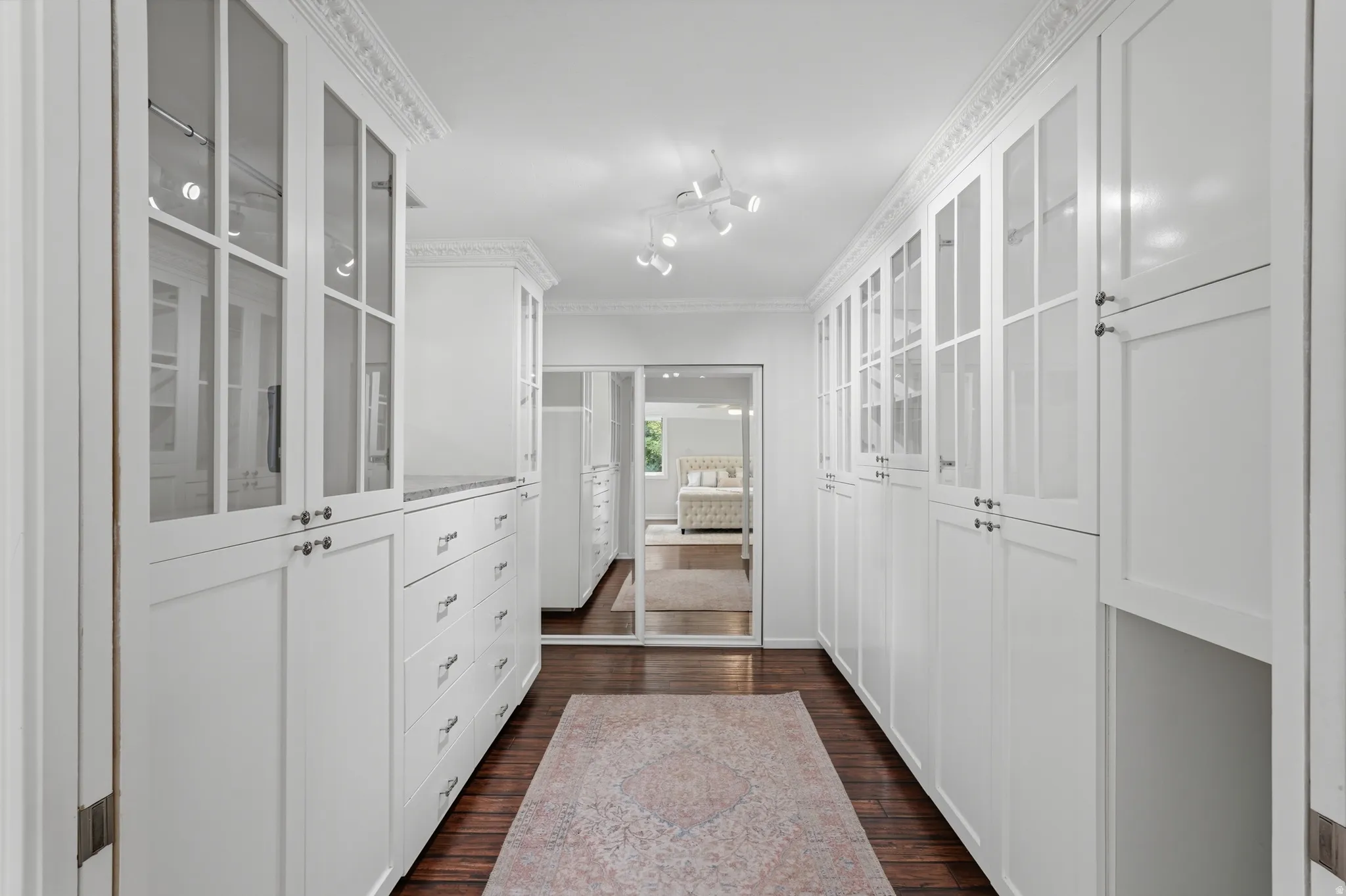 Custom white cabinetry with glass-front uppers, built-in drawers, and dark wood-finish flooring