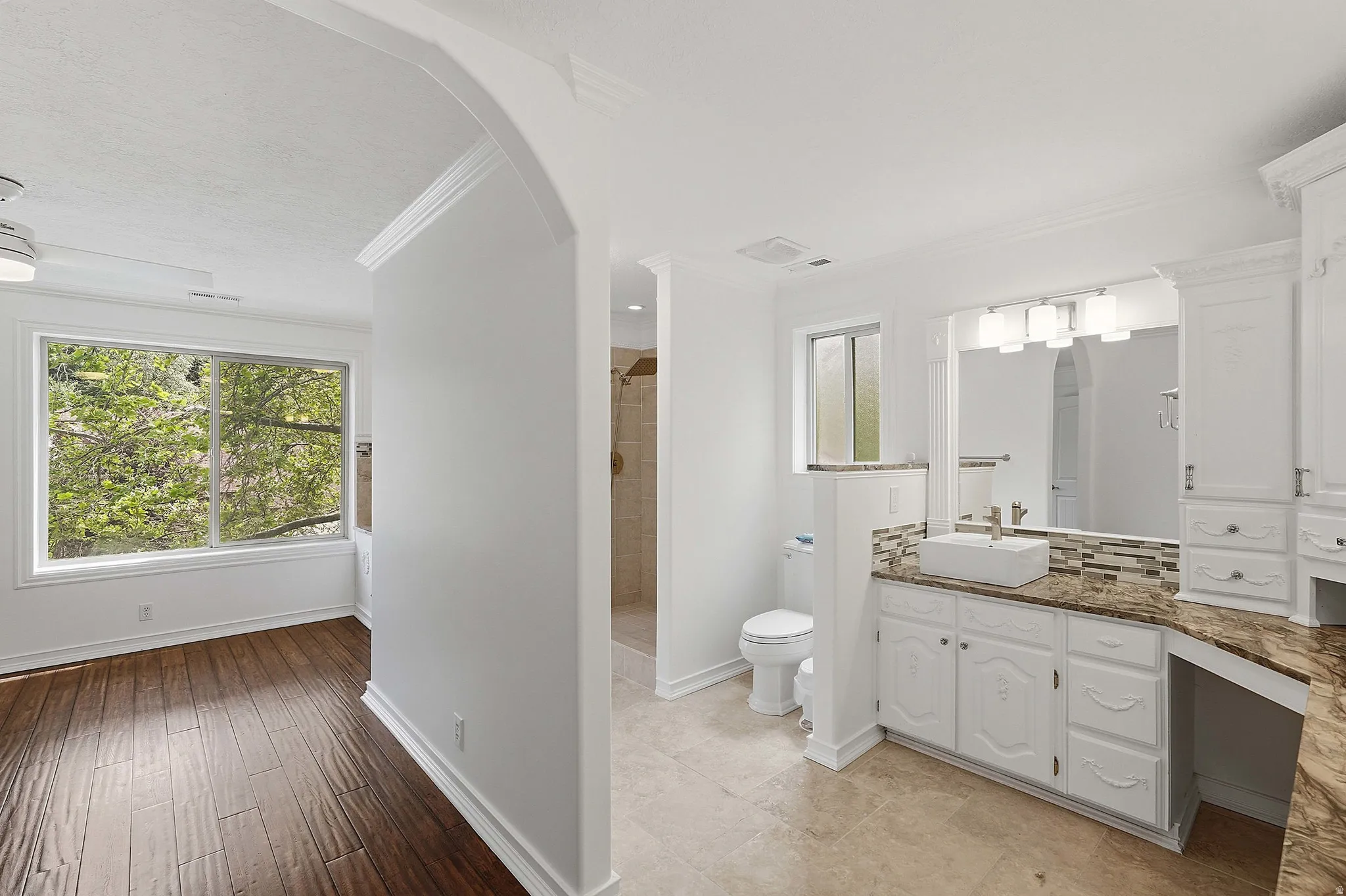 Spacious bathroom featuring a vessel sink, an expansive vanity with storage, a large mirror, and tiled flooring