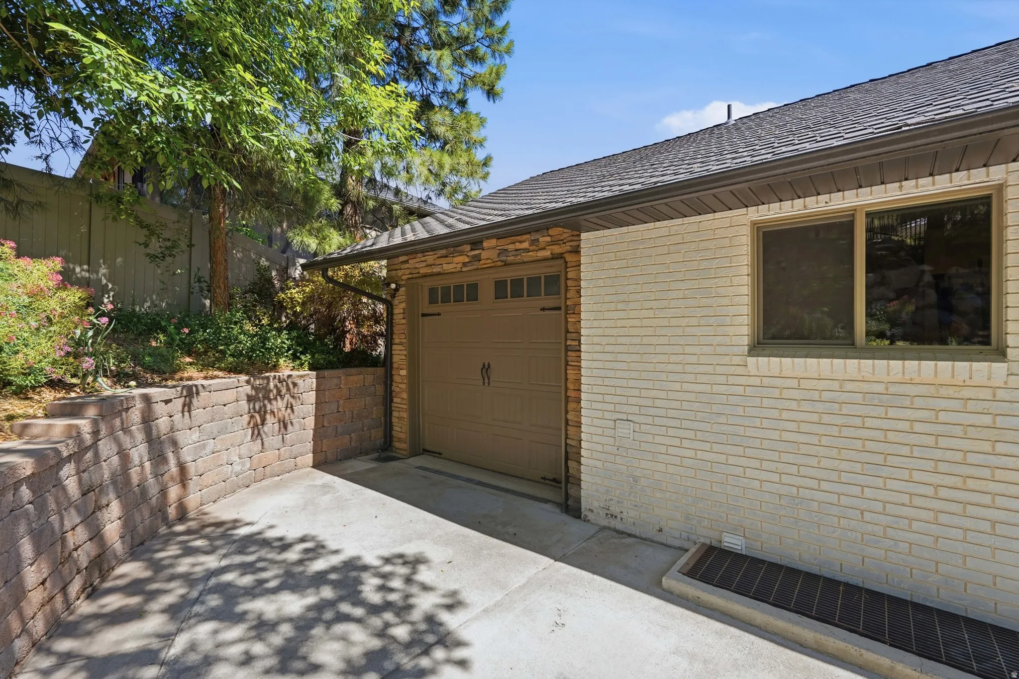 Attached garage featuring a decorative overhead door and stone veneer detailing