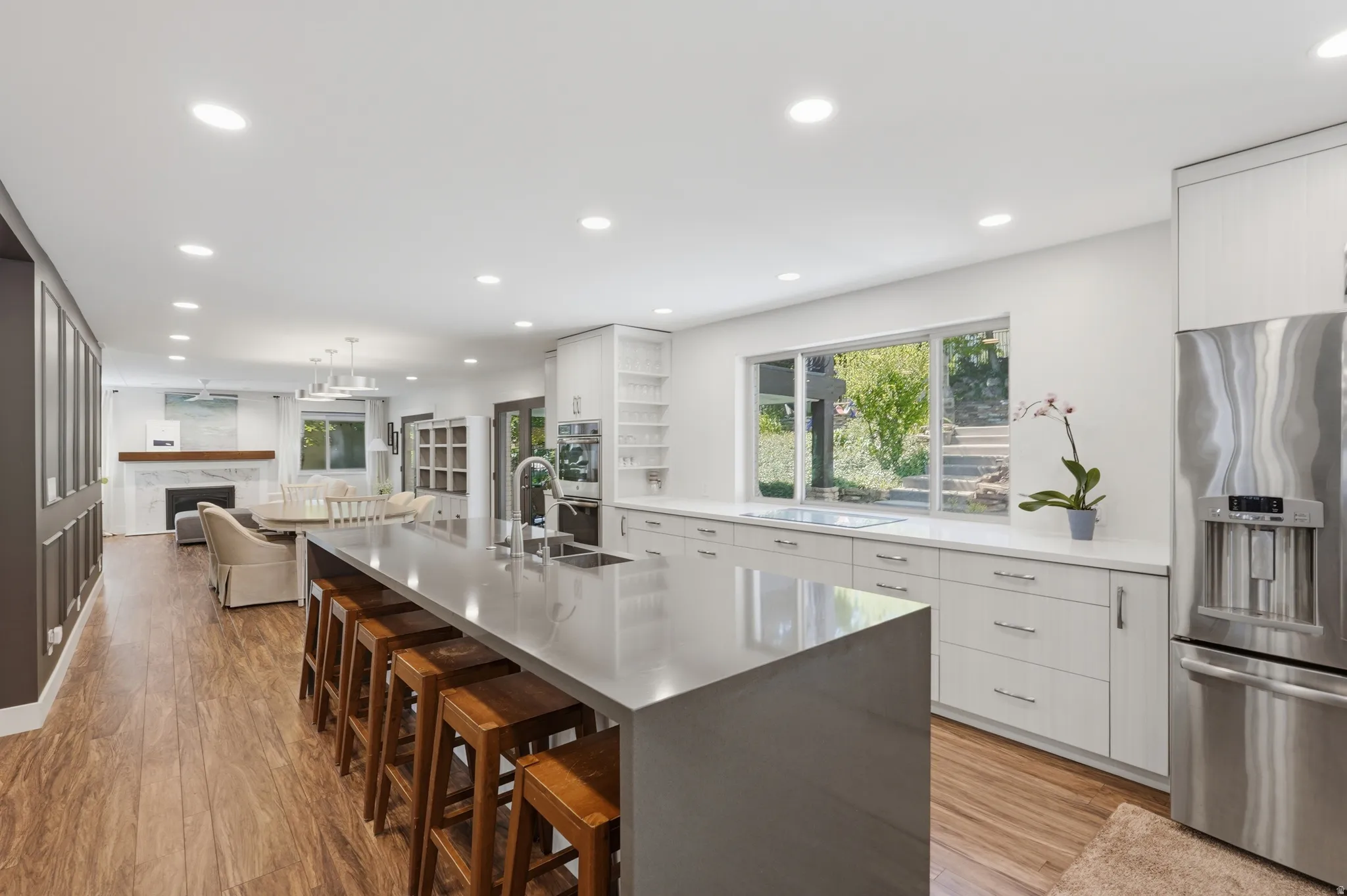 Open-concept kitchen featuring an expansive island with seating, stainless steel appliances, white cabinetry, and recessed lighting