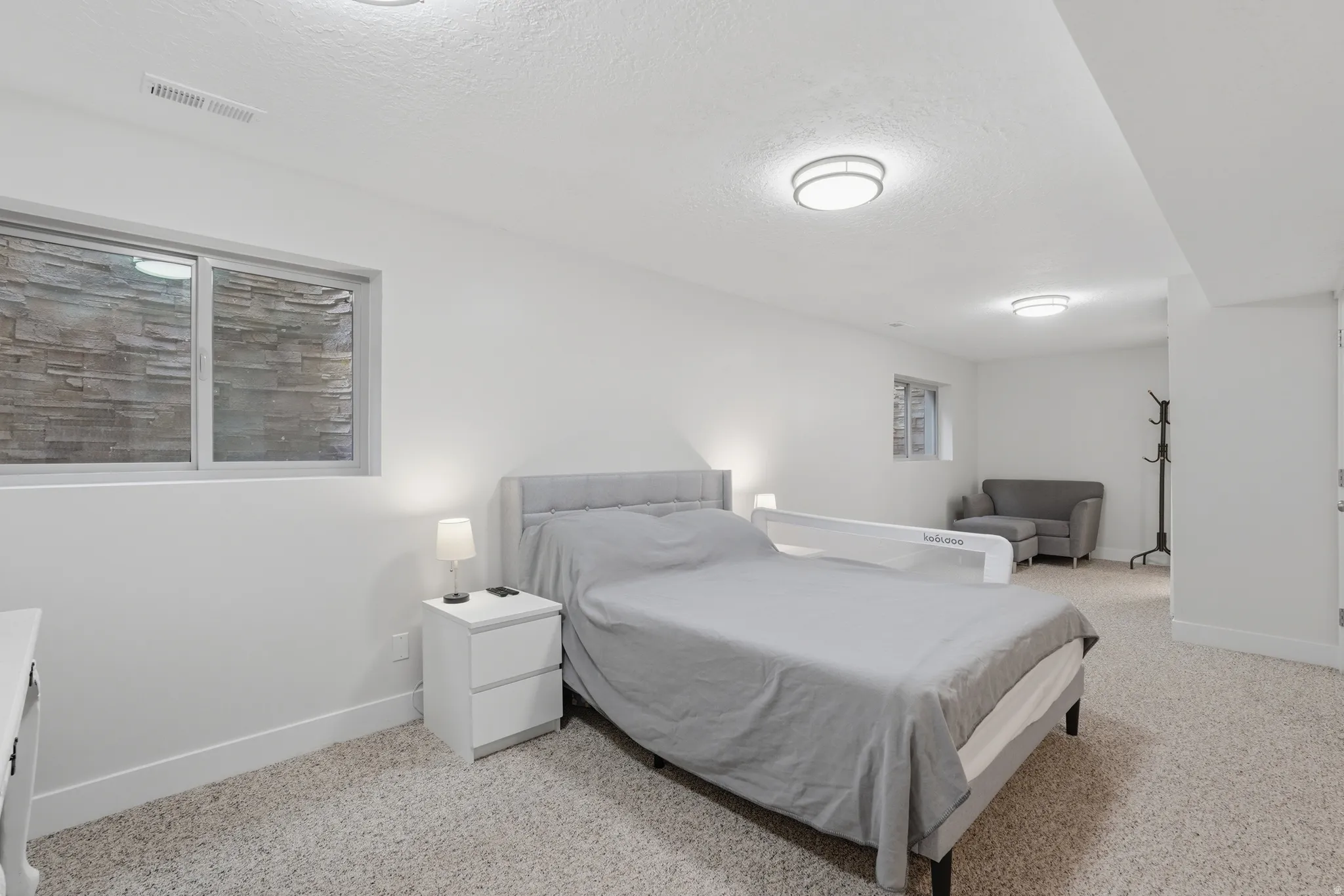 Carpeted room featuring a window with a stone-clad exterior wall, recessed lighting, and a neutral color palette
