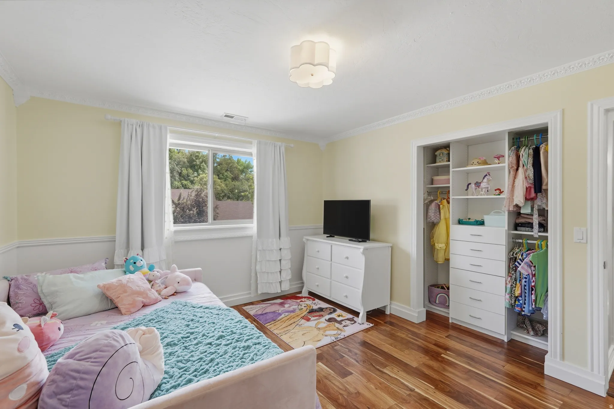 Bedroom featuring wood-finish flooring, a double-pane window, and white crown molding