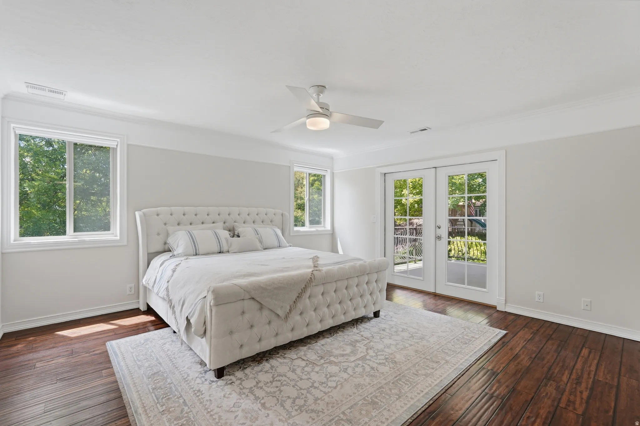 Spacious room featuring rich wood-finish flooring, white trim, and a ceiling fan