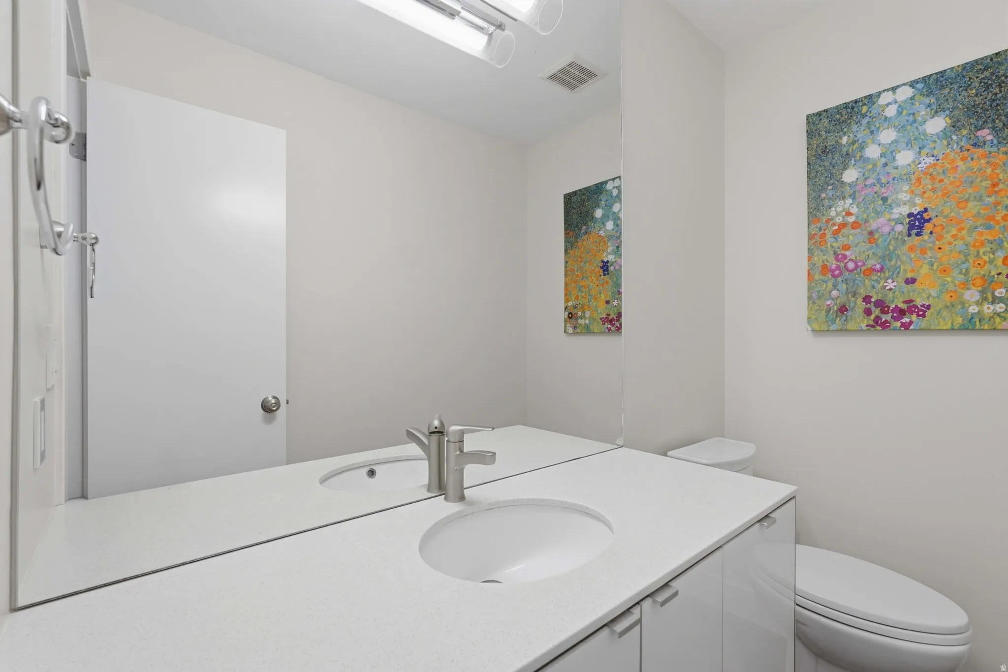 Contemporary vanity featuring a white countertop with integrated sinks, brushed nickel faucets, and sleek white cabinetry