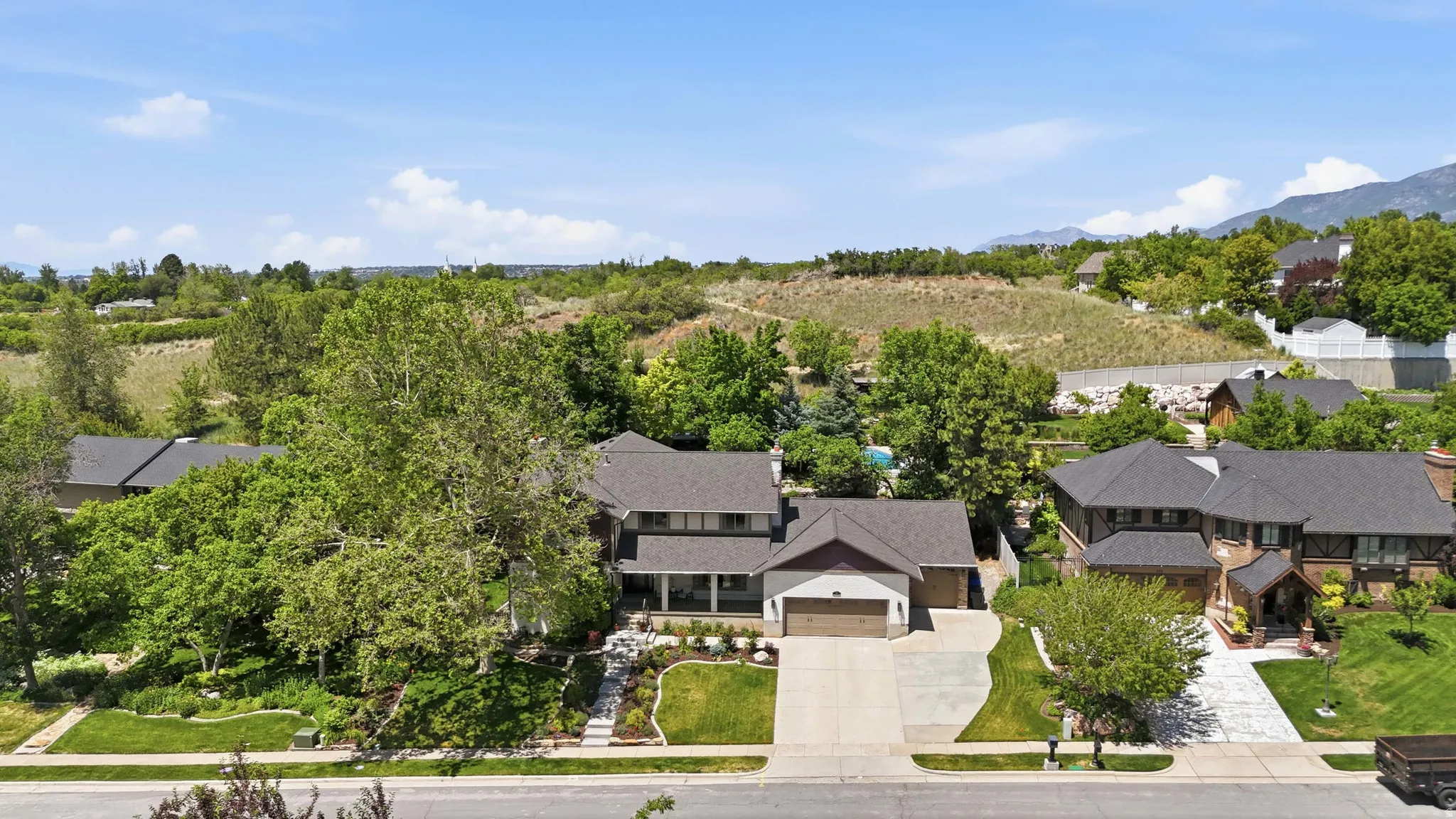Contemporary two-story residence featuring a two-car garage, established landscaping, and a paved driveway