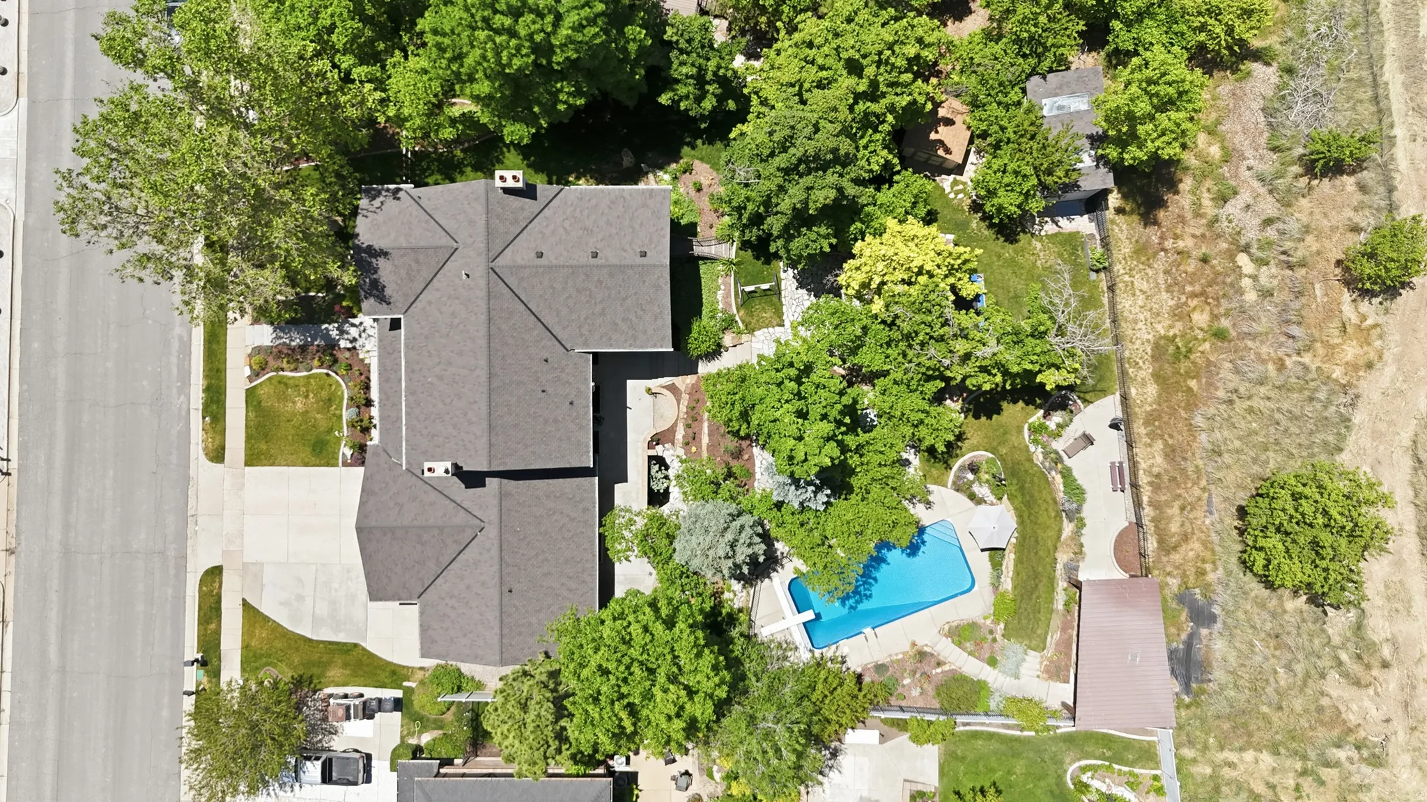 Expansive property featuring a multi-gabled main residence with a dark shingle roof, a spacious driveway, and mature landscaping
