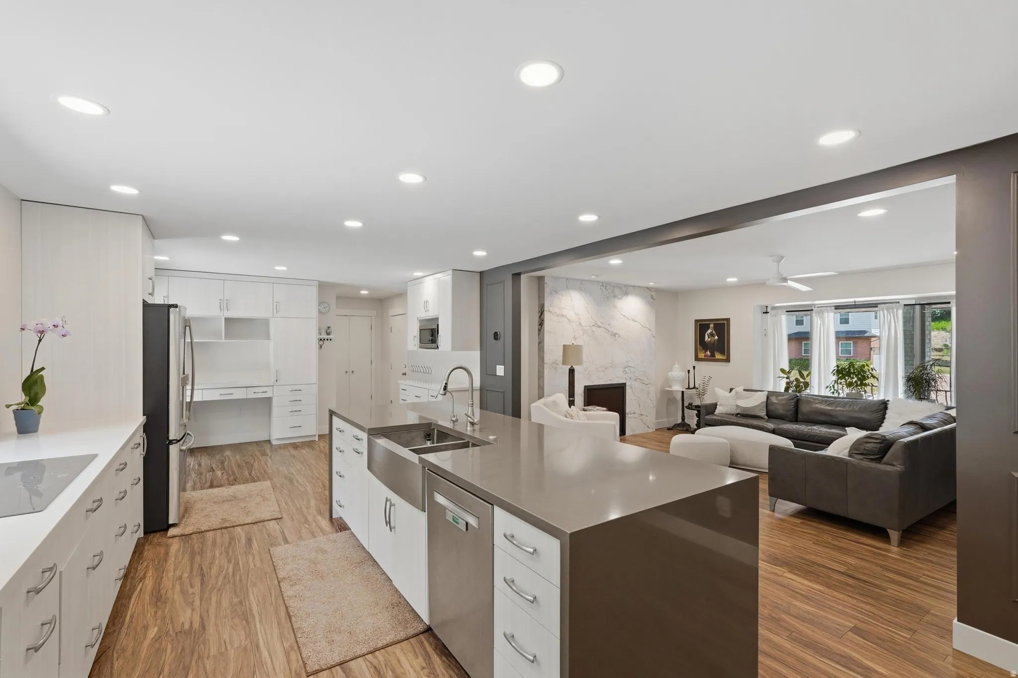 Open concept kitchen featuring a large island with a farmhouse sink, stainless steel dishwasher, and ample counter space