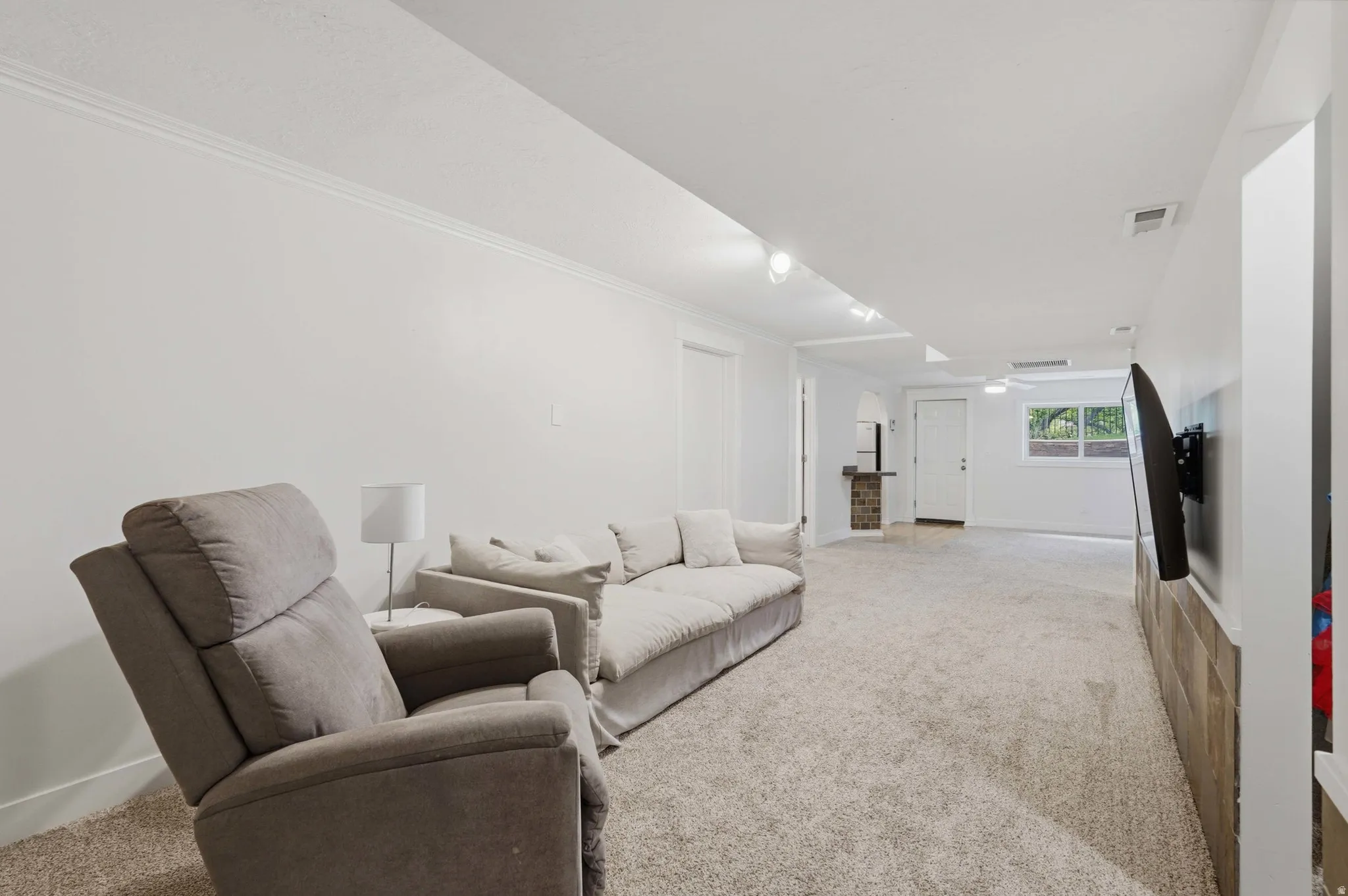 Spacious carpeted room featuring white walls and crown molding