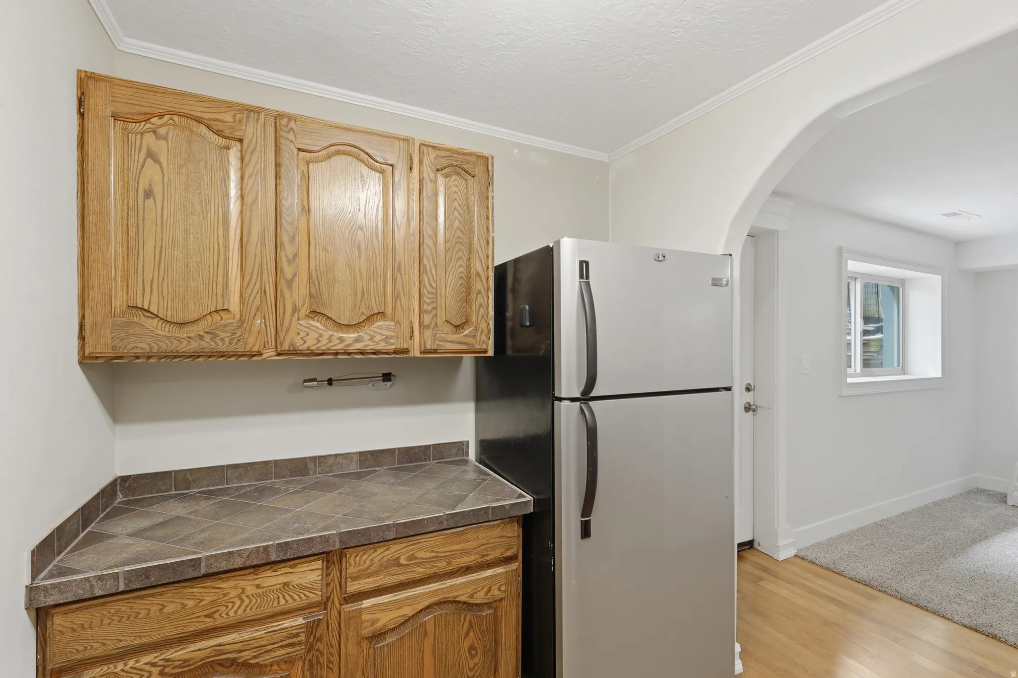 Kitchenette featuring oak cabinetry, tile countertop, and a stainless steel refrigerator
