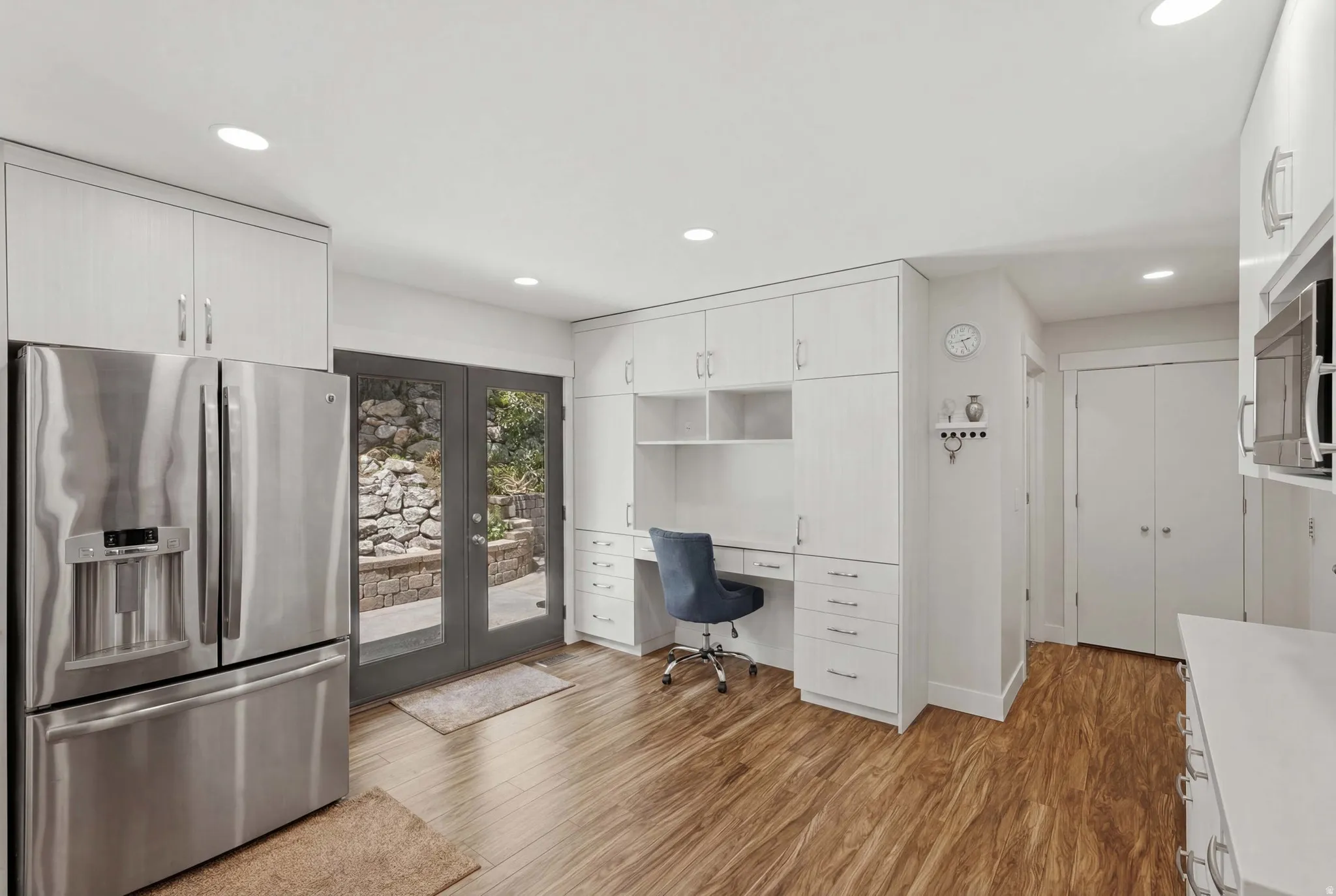 Bright kitchen area featuring wood-finish flooring, white cabinetry, and recessed lighting