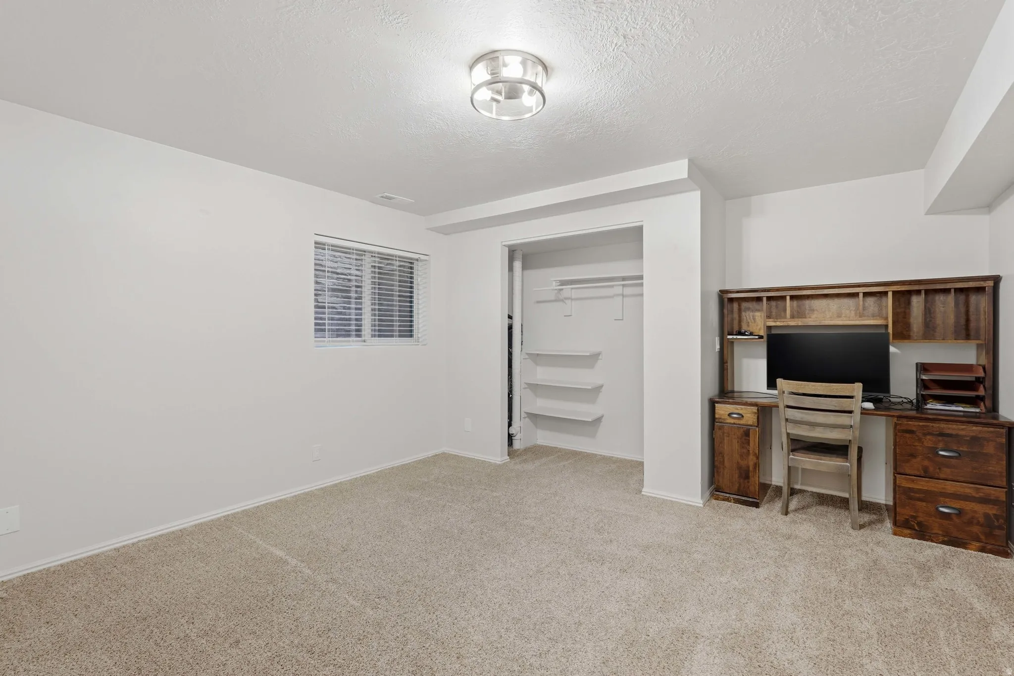 Carpeted room featuring a window with blinds, recessed lighting, and an open closet with shelving and hanging rod