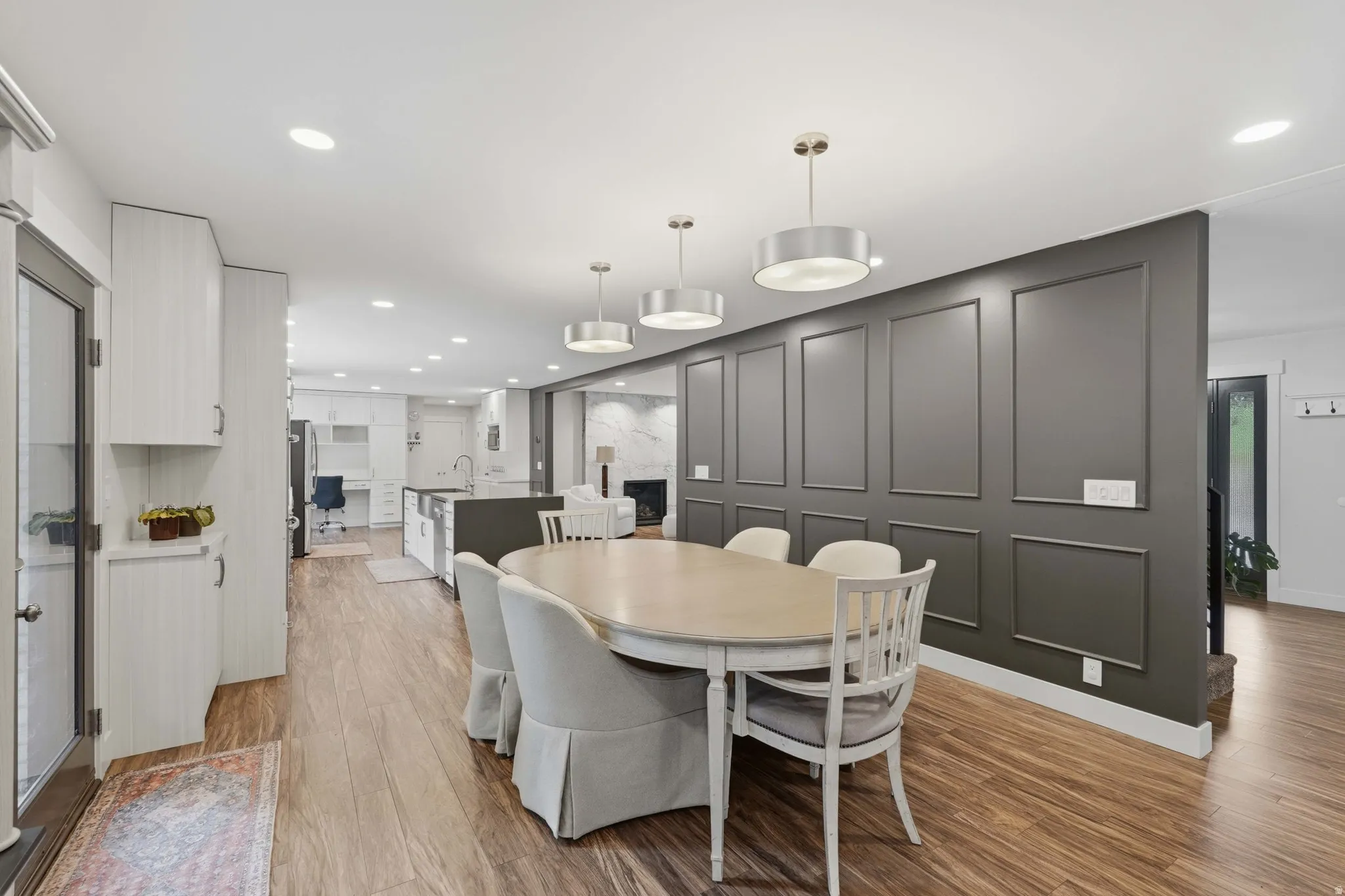 Dining area with wood-finish flooring, featuring a decorative paneled accent wall