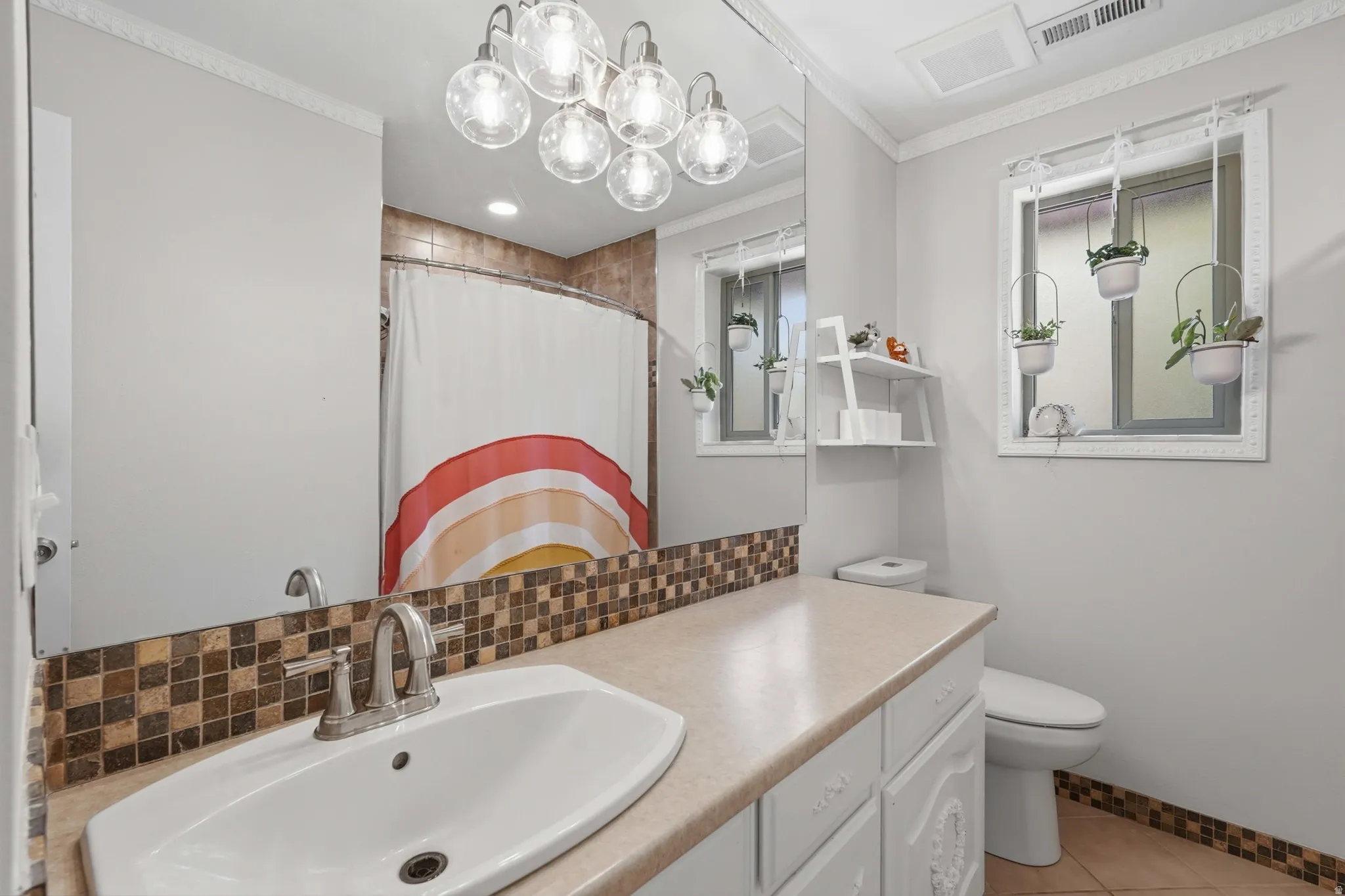 Bathroom featuring a vanity with a white basin sink, brushed nickel faucet, and a tiled backsplash