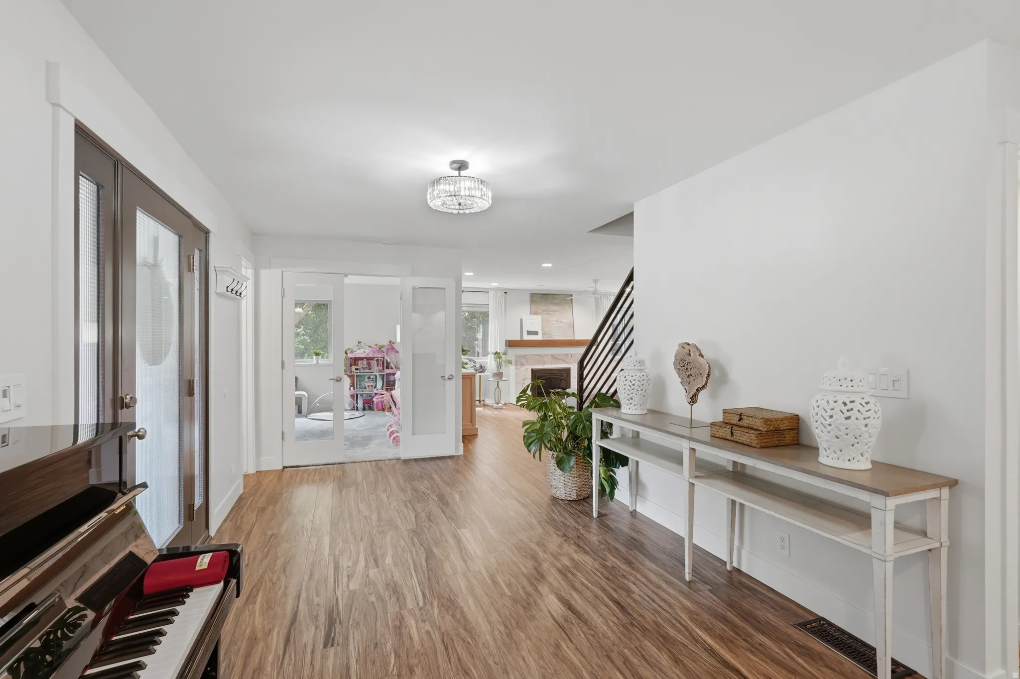 Spacious entryway featuring wood-finish flooring, a contemporary chandelier, white walls, and a console table